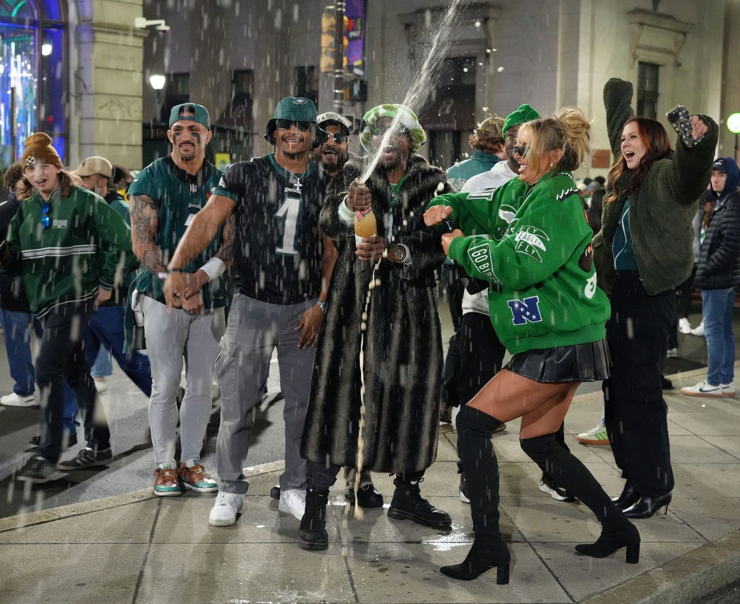 A person wearing a green sports jersey leads a dance routine in what appears to be a busy indoor space.