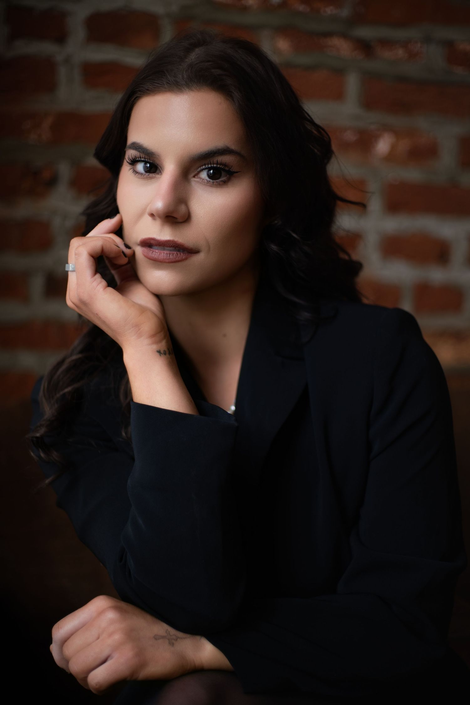 Professional portrait series against brick wall showing elegant poses in dark clothing with dramatic lighting and shadows.