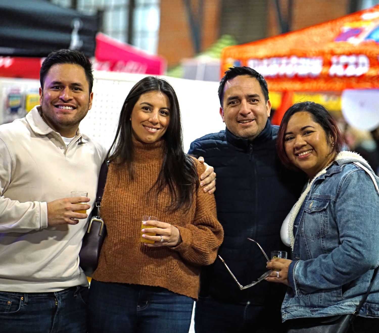 A group of friends enjoying drinks and conversation at a casual gathering with warm lighting and festive atmosphere.
