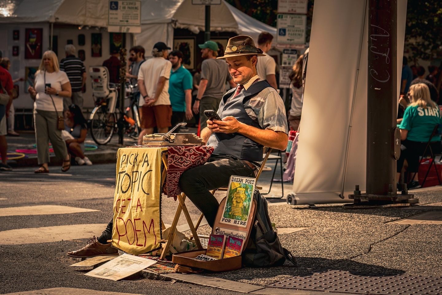 Street performer sitting and drawing art for tourists in an outdoor marketplace.