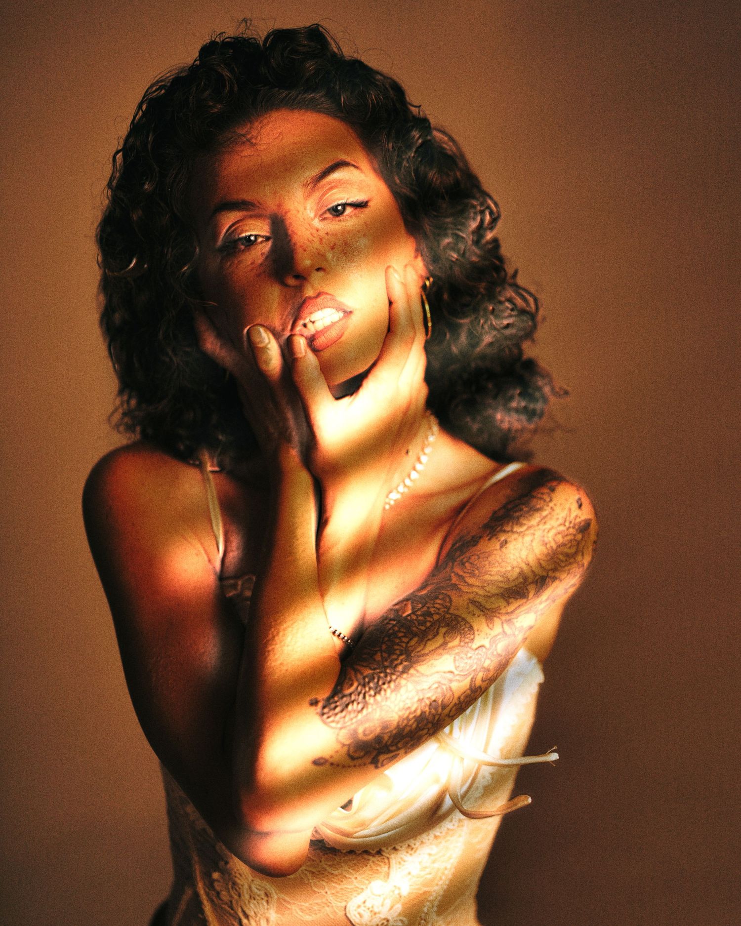 Artistic portrait with dramatic lighting and shadows creating stripes across a glamorous pose.