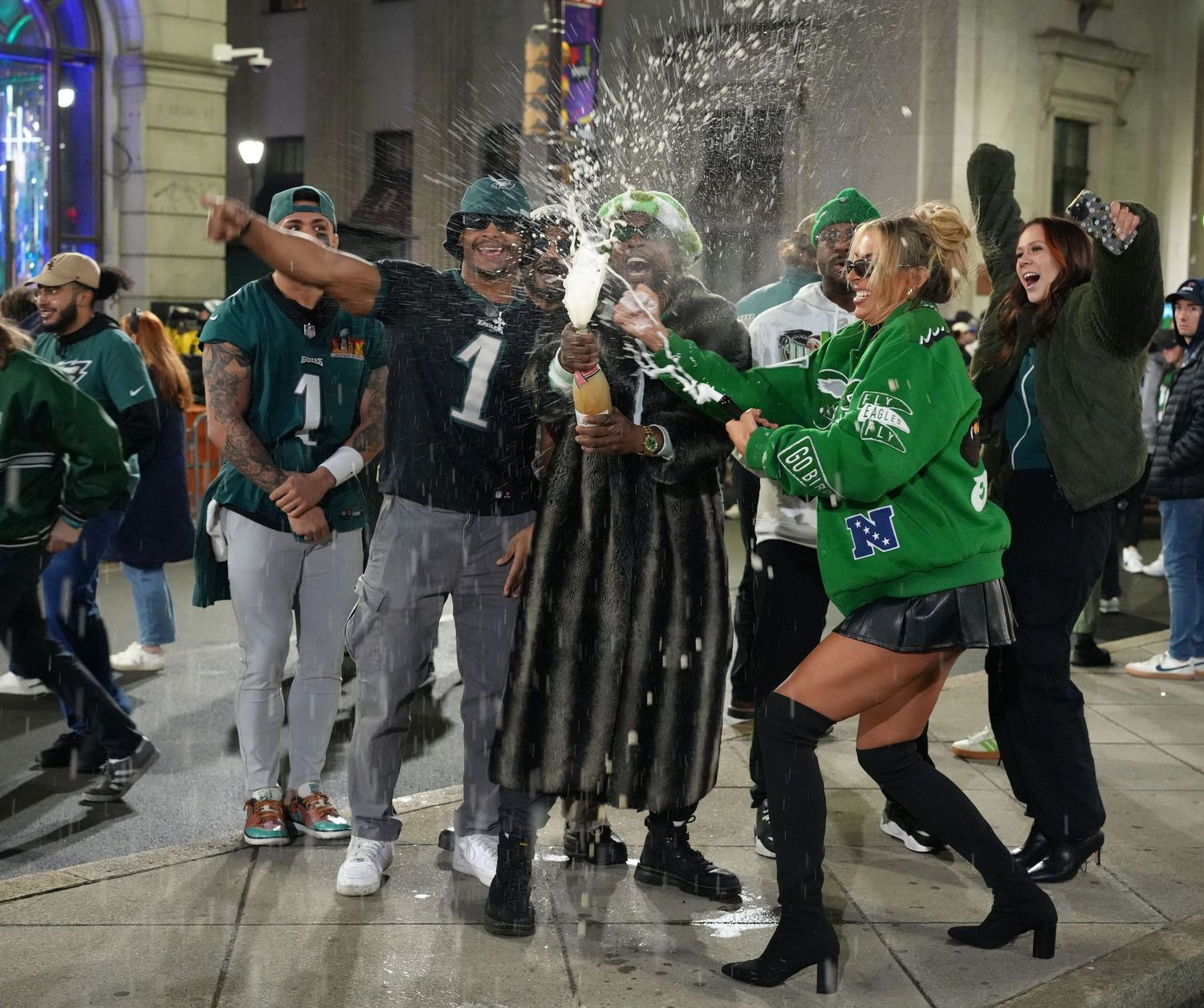 Philadelphia Eagles fans celebrate in the streets wearing team jerseys and green attire after a victory.