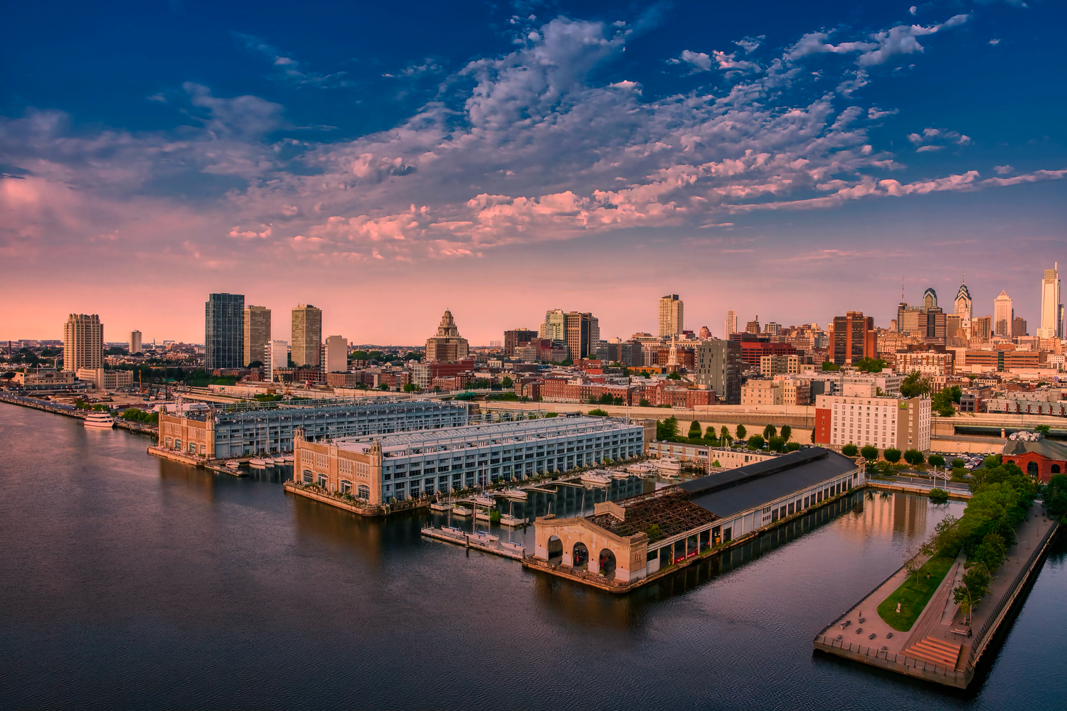 Panoramic aerial photo of Baltimore Inner Harbor cityscape with boats and piers during sunset.
