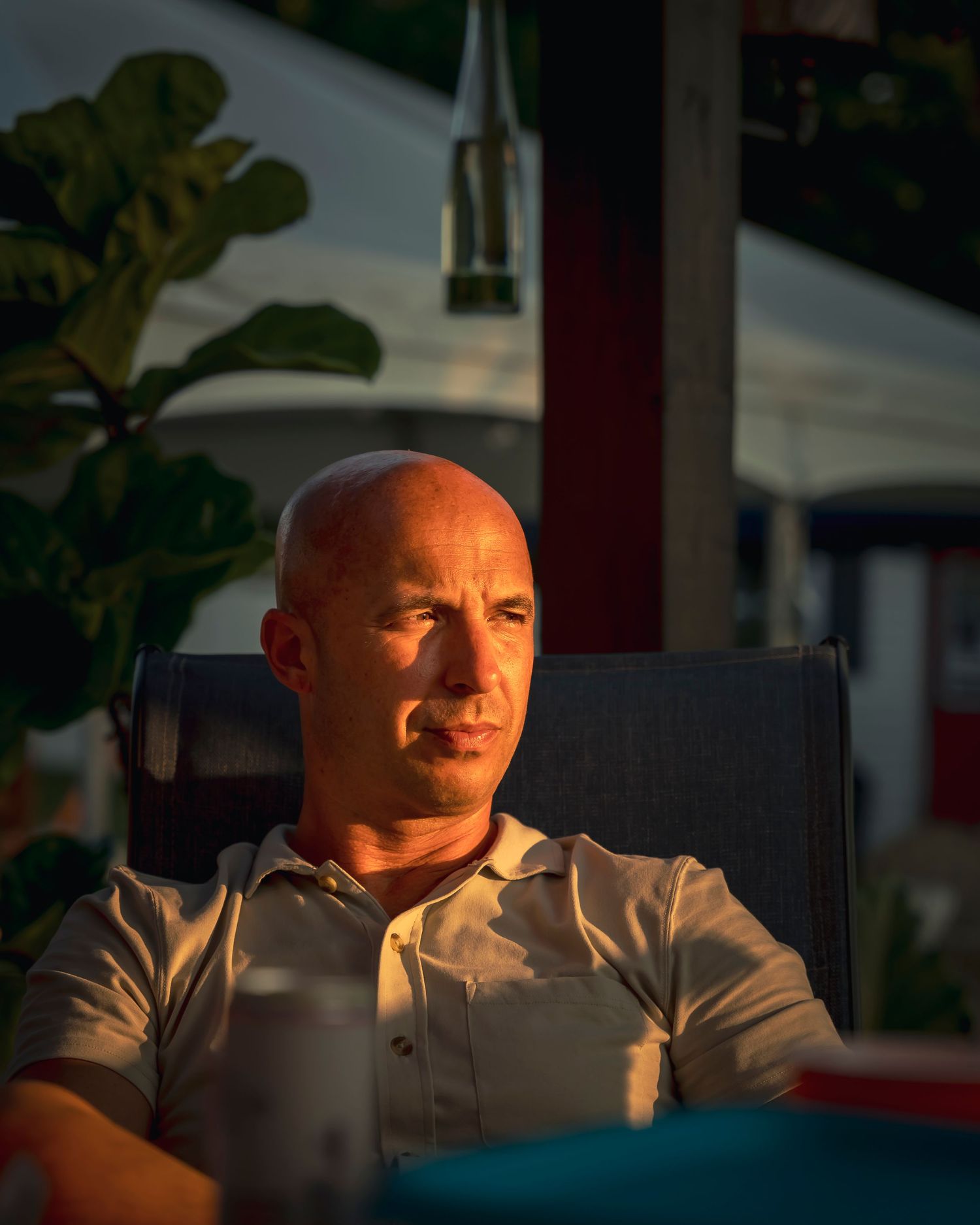 Person sitting in a chair at sunset with warm golden lighting casting dramatic shadows across their face.