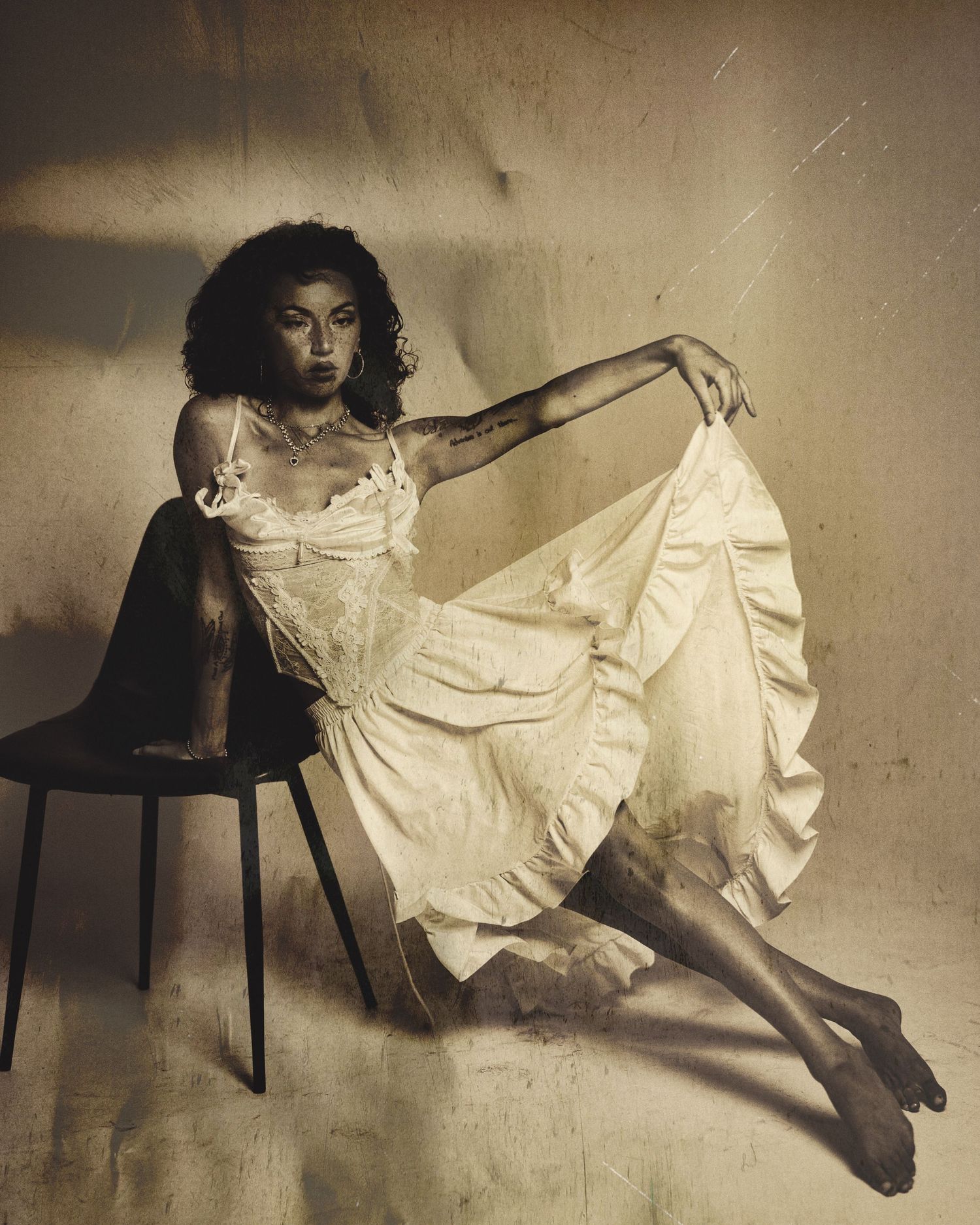 A series of sepia-toned artistic photographs showing a figure in a white dress posing gracefully on dark furniture.