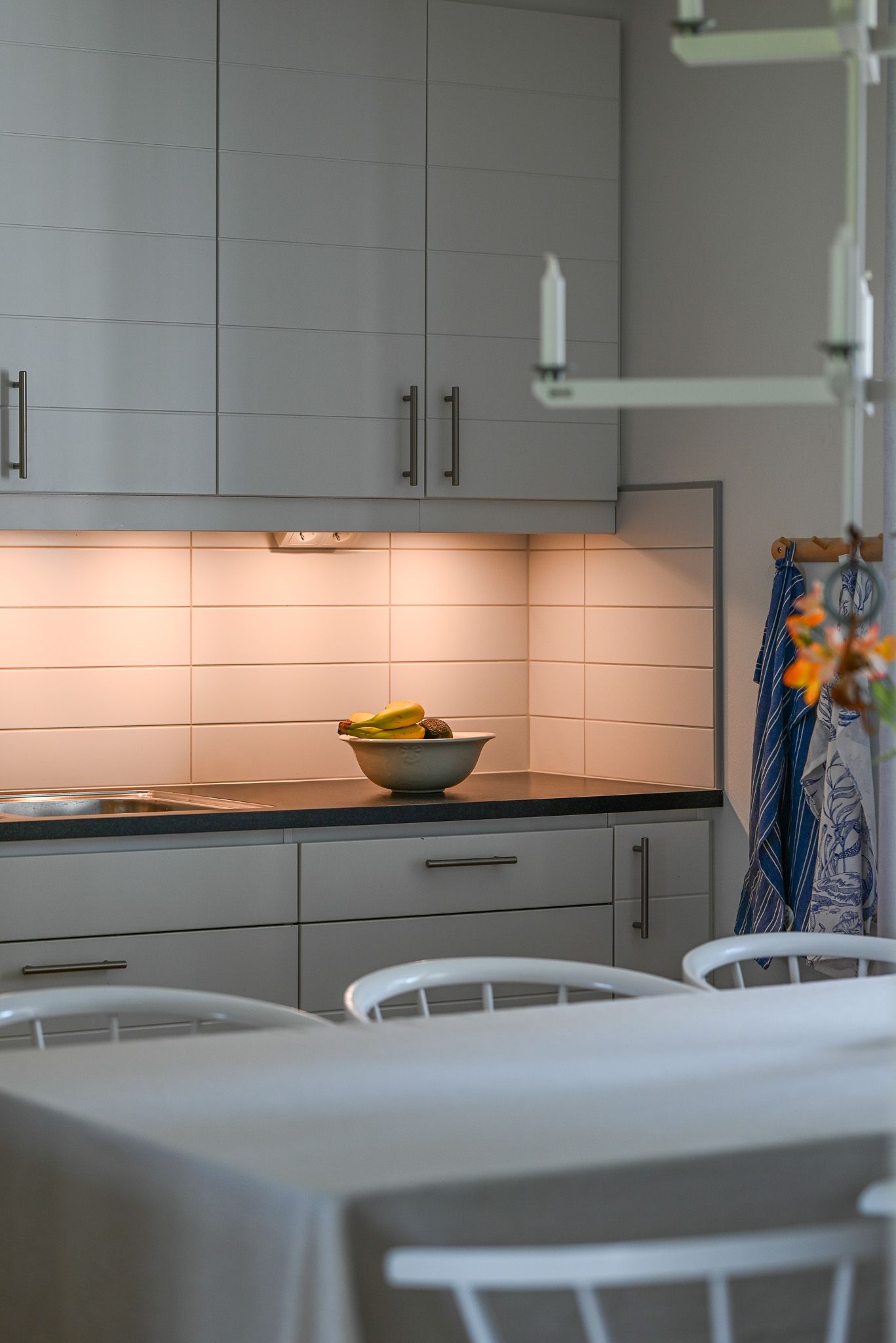 Modernt kök med belysning över arbetsyta med fruktskål ståendes som detalj.