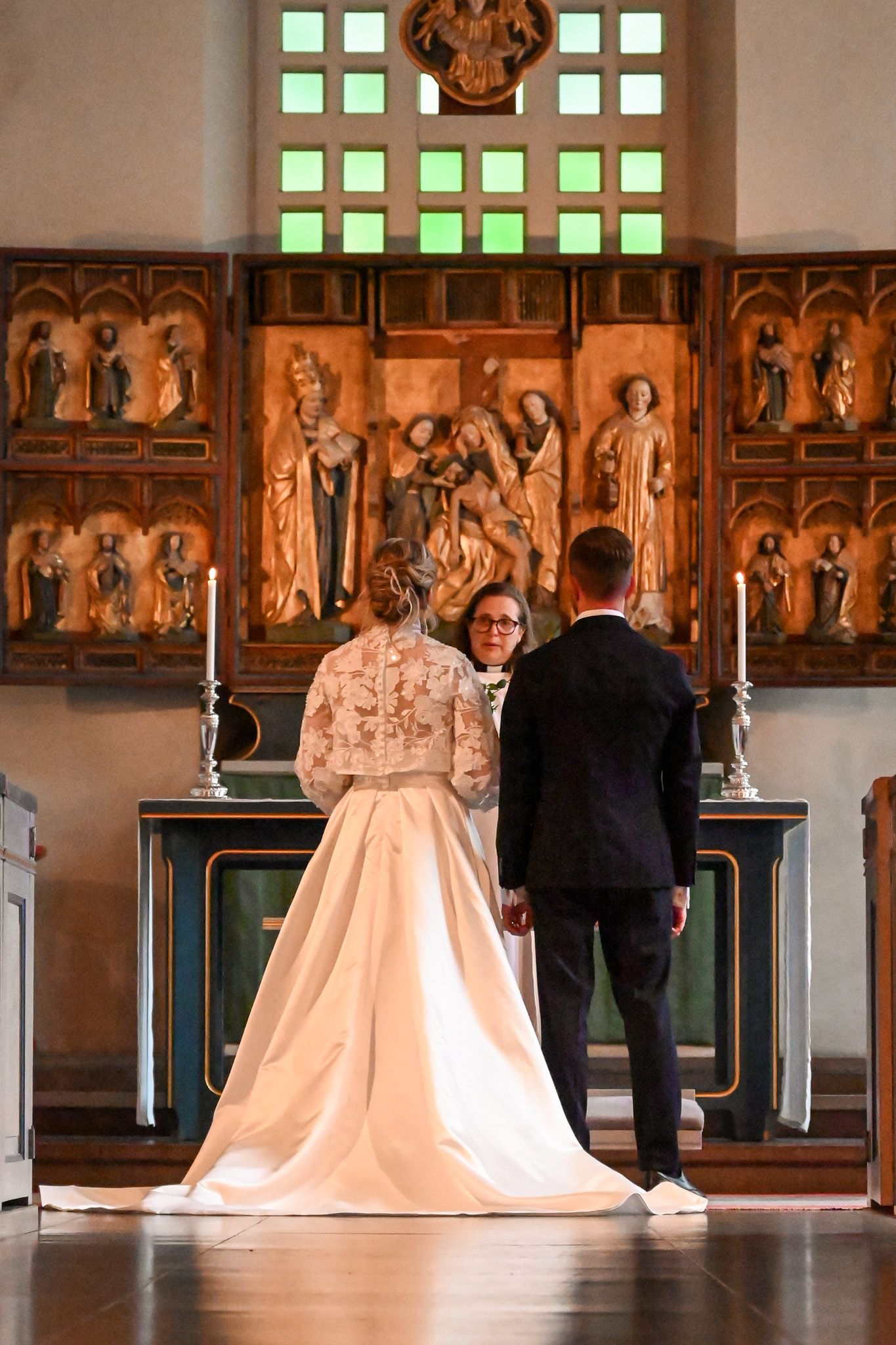 Vigsel i historisk kyrka med brudparet sett bakifrån.