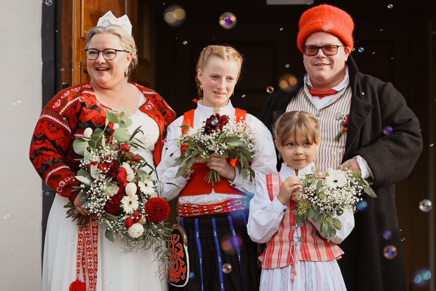 Bröllopsfoto vid utgång från kyrkan med brudtärnor som bär buketter där alla har folkdräkt på sig.