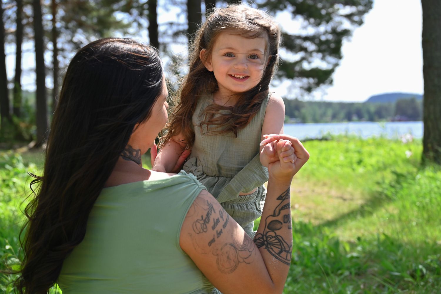 Mamma och hennes dotter leker och njuter av solen under gravidfotografering.