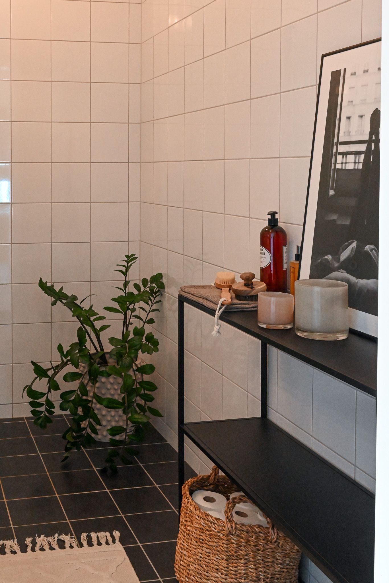 Detaljbild för att höja feel good känslan i boendet med stor grön växt på svart klinkersgolv och vita kakelväggar ger en modern touch.