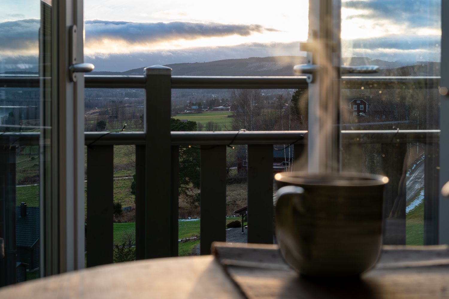 Panoramavy över landskap med kaffekopp i förgrunden för att ge känsla av avkoppling.
