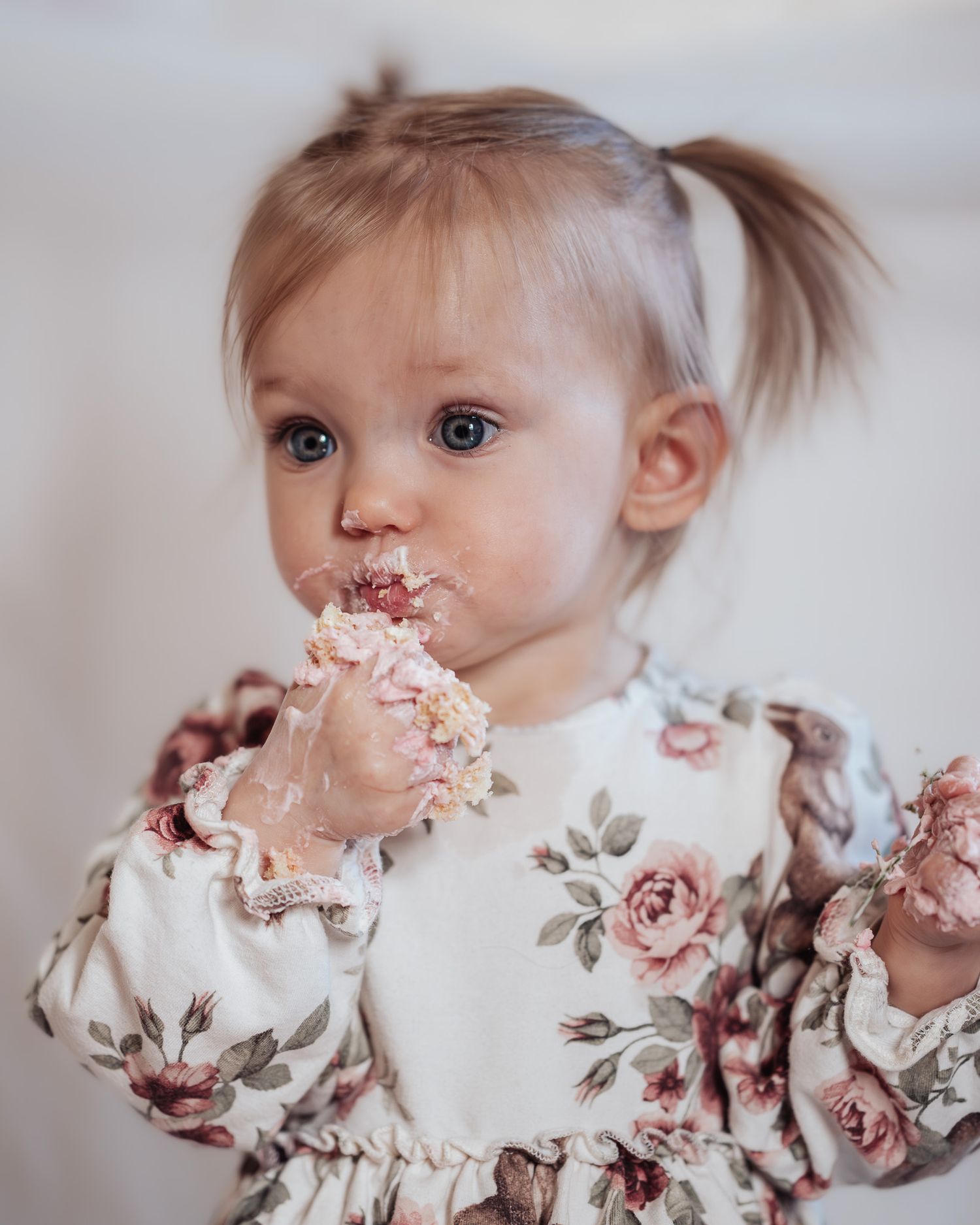 Barn i klänning under smash the cake fotografering med tårta i handen och i ansiktet.
