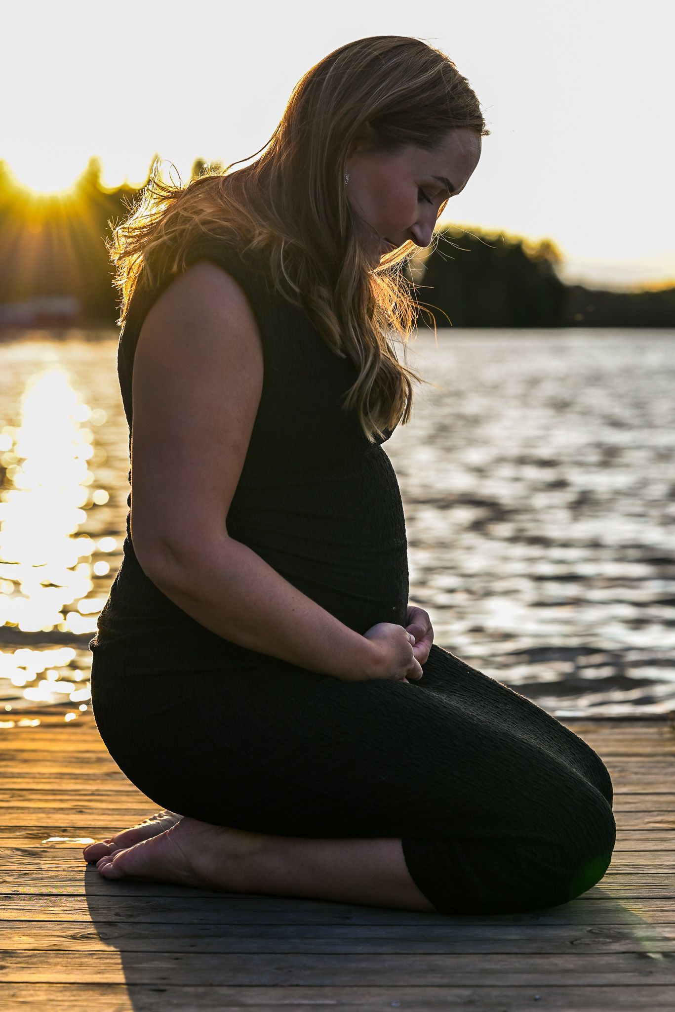 Gravid glow på brygga i solnedgången vid lugn sjö.