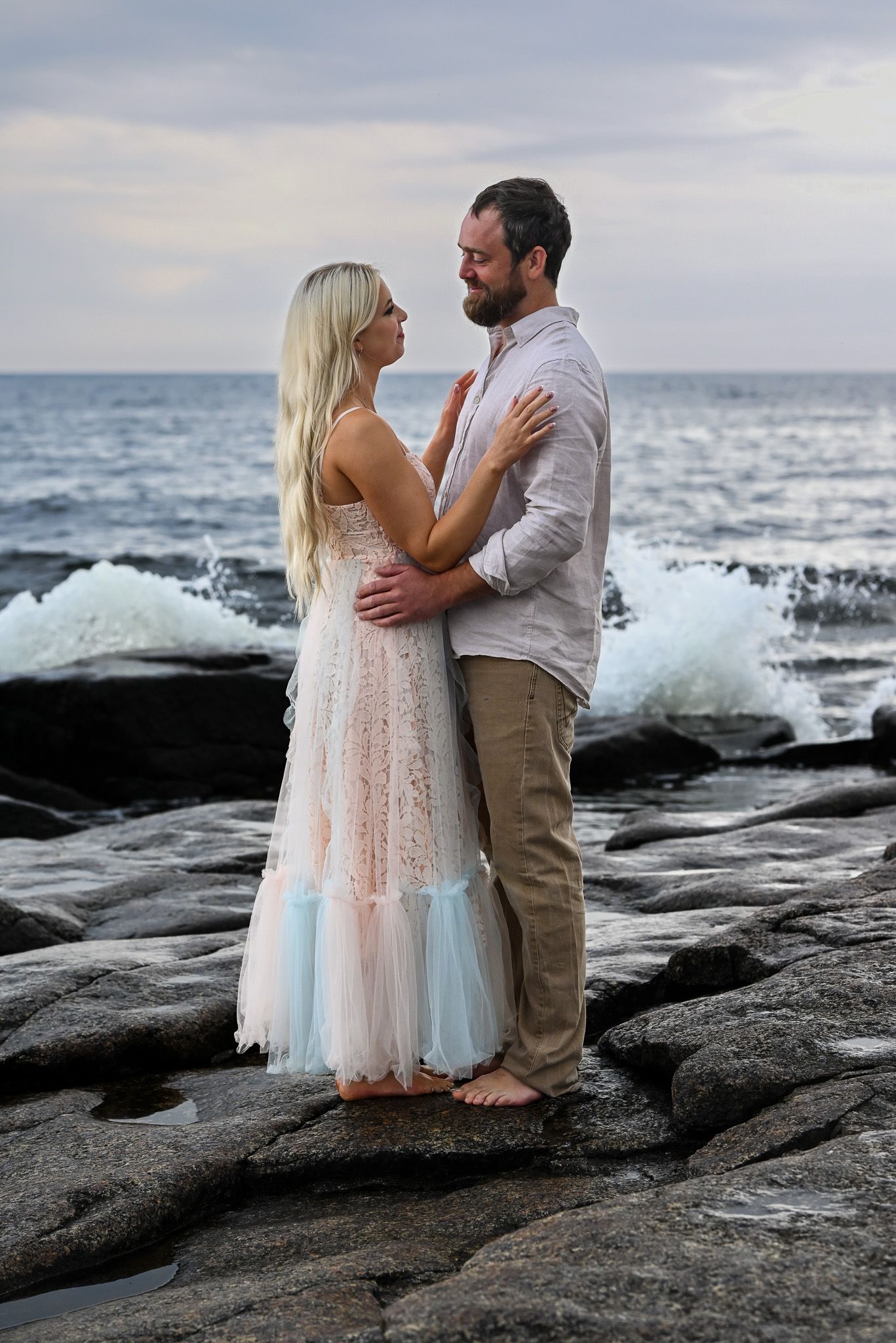 Romantisk fotosession vid havet i solnedgången i pastellfärgad klänning och linneklädsel.