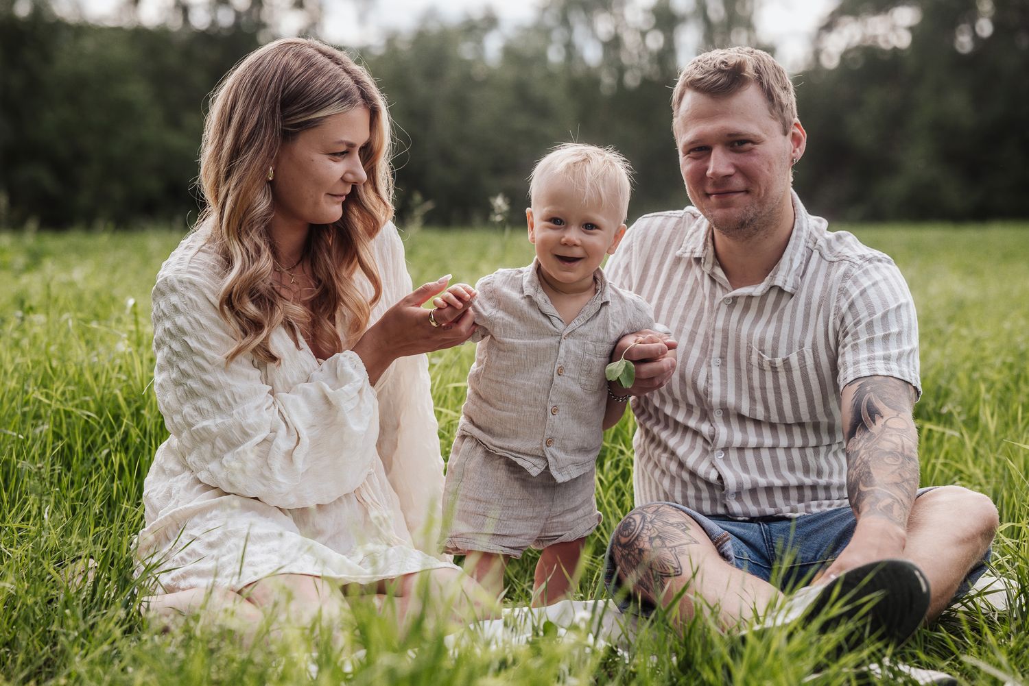 Lycklig familj på en sommaräng under fotografering tillsammans med deras son.