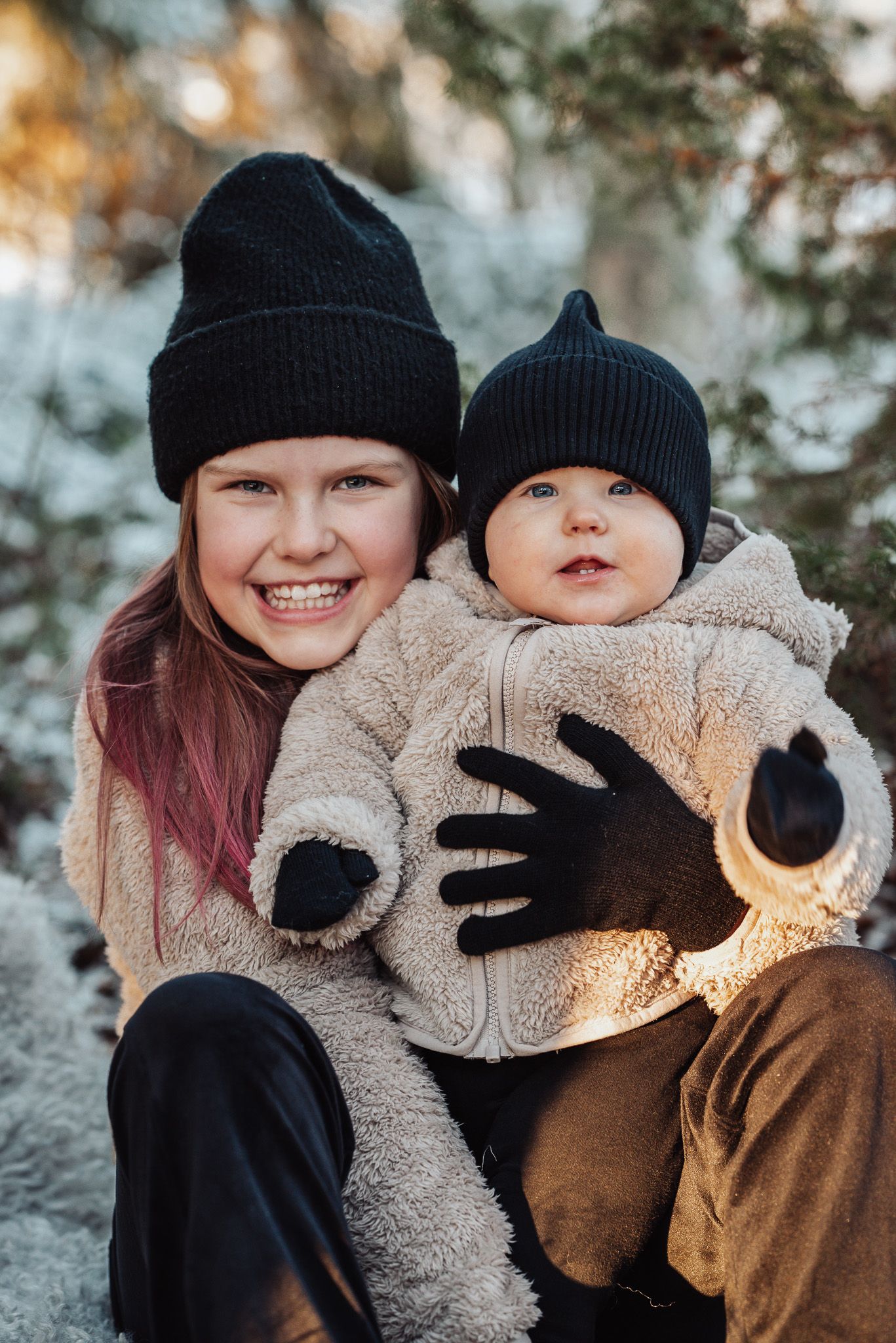 Syskonfotografering ute i snön under vintern och golden hour med mysig stämning.