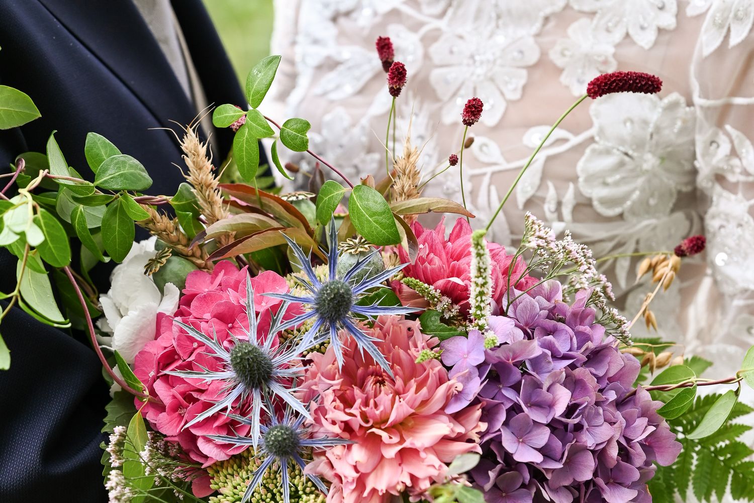 Beautiful wedding bouquet featuring pink carnations, purple flowers and delicate greenery.