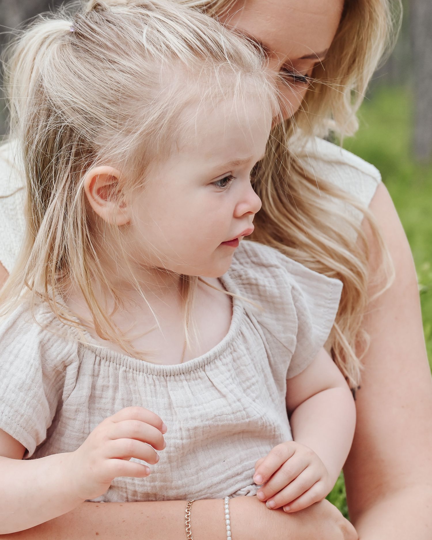 A small child in a light colored dress leans close to someone wearing a floral print dress in a series of photos.
