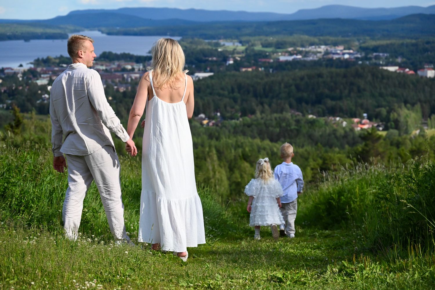 Familj med barn på berg med vacker utsikt över Hälsinglands berg och sjöar i grönskande landskap.