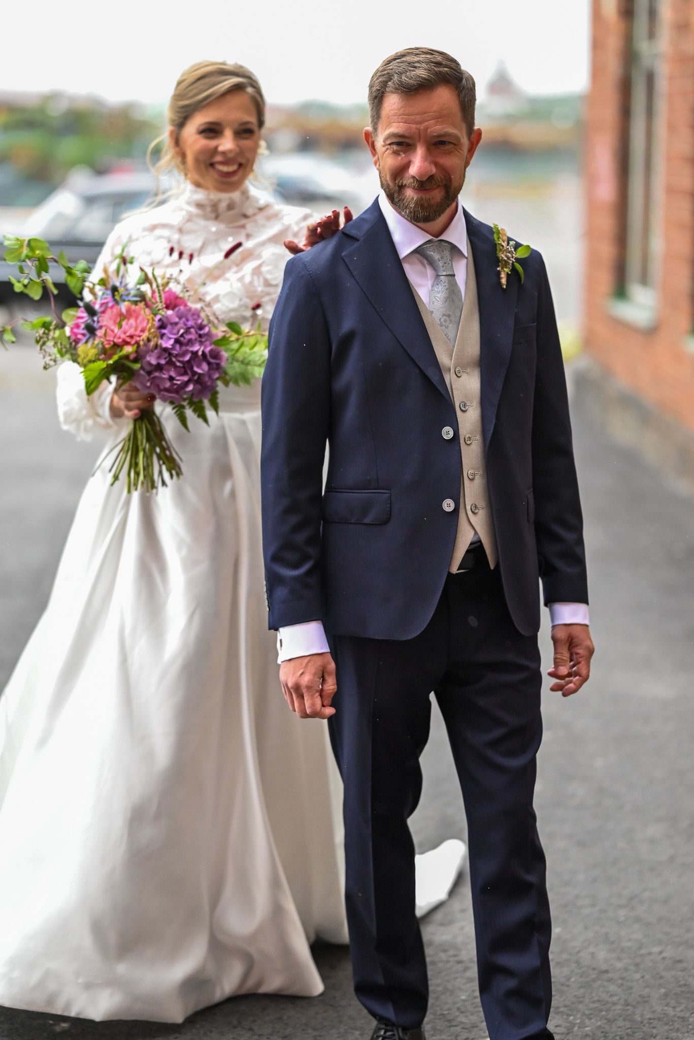First look vid tegelbyggnad med en lila och färgglad bukett blommor.