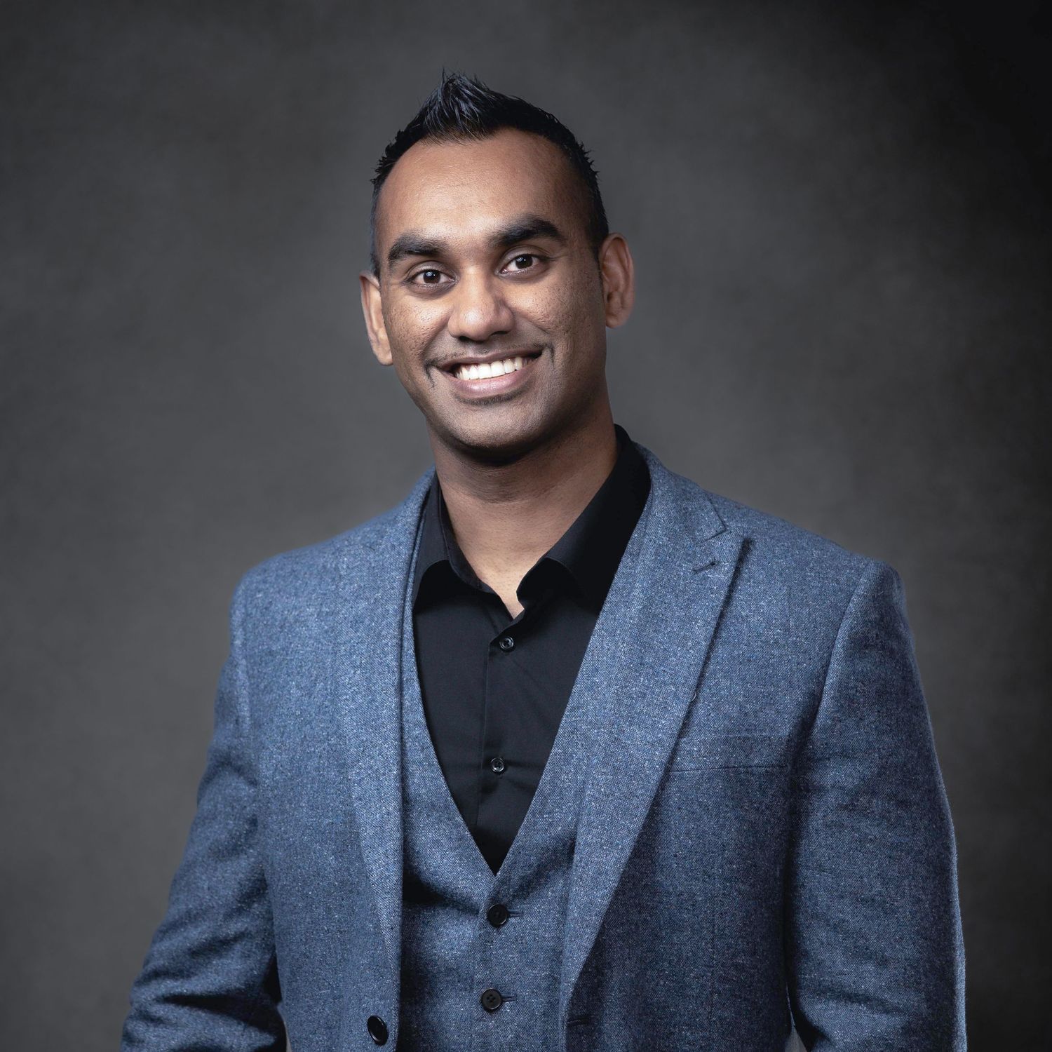 Amit in a blue blazer and black shirt poses confidently against a dark studio background. Aerial Site Intelligence