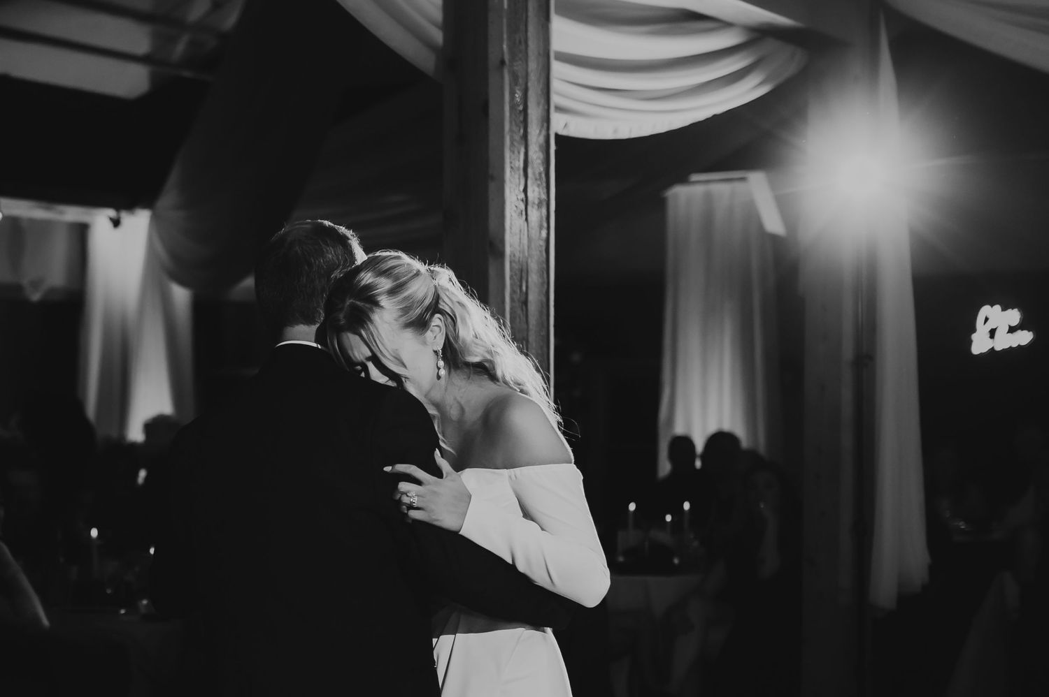 Black and white photo of a bride and groom sharing their first dance at a romantic wedding reception.