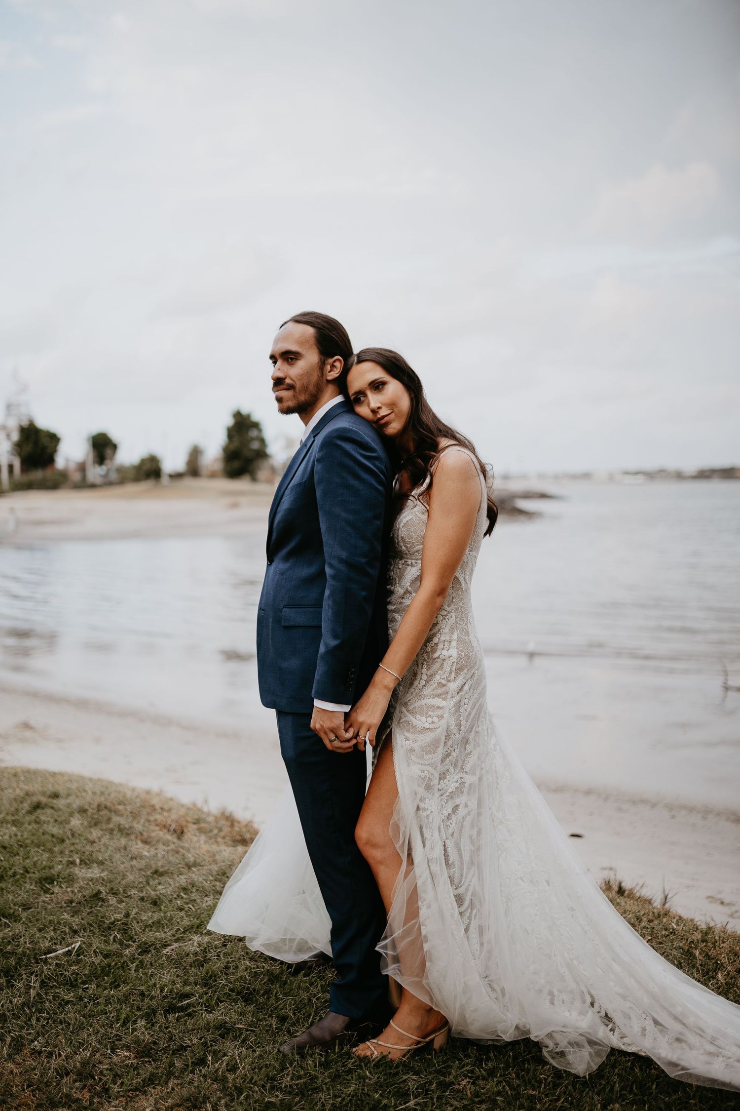A couple in wedding attire embraces on a cloudy beach in a series of romantic photos.
