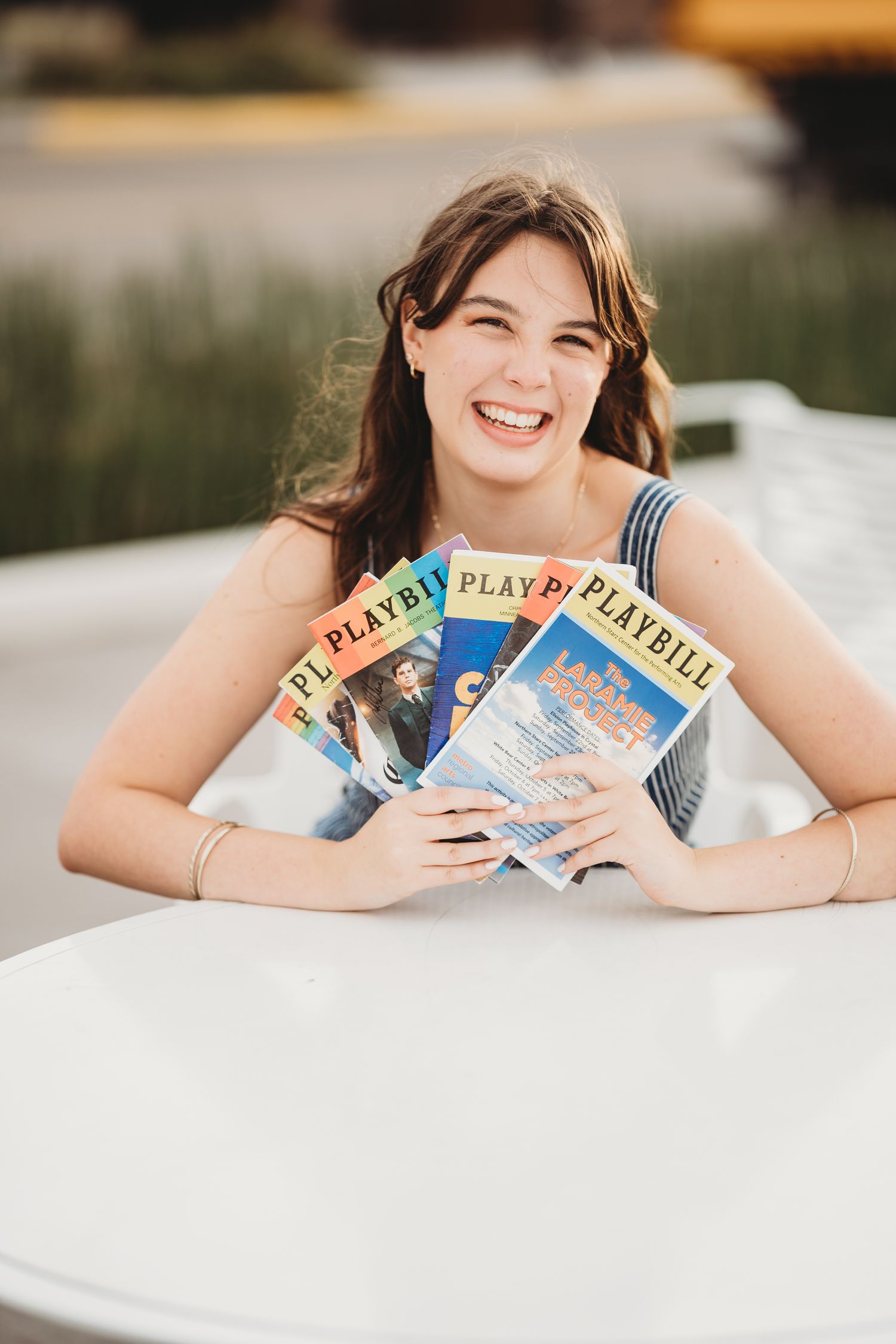 A person lies on the ground while holding vintage Playboy magazines in an outdoor photoshoot setting.