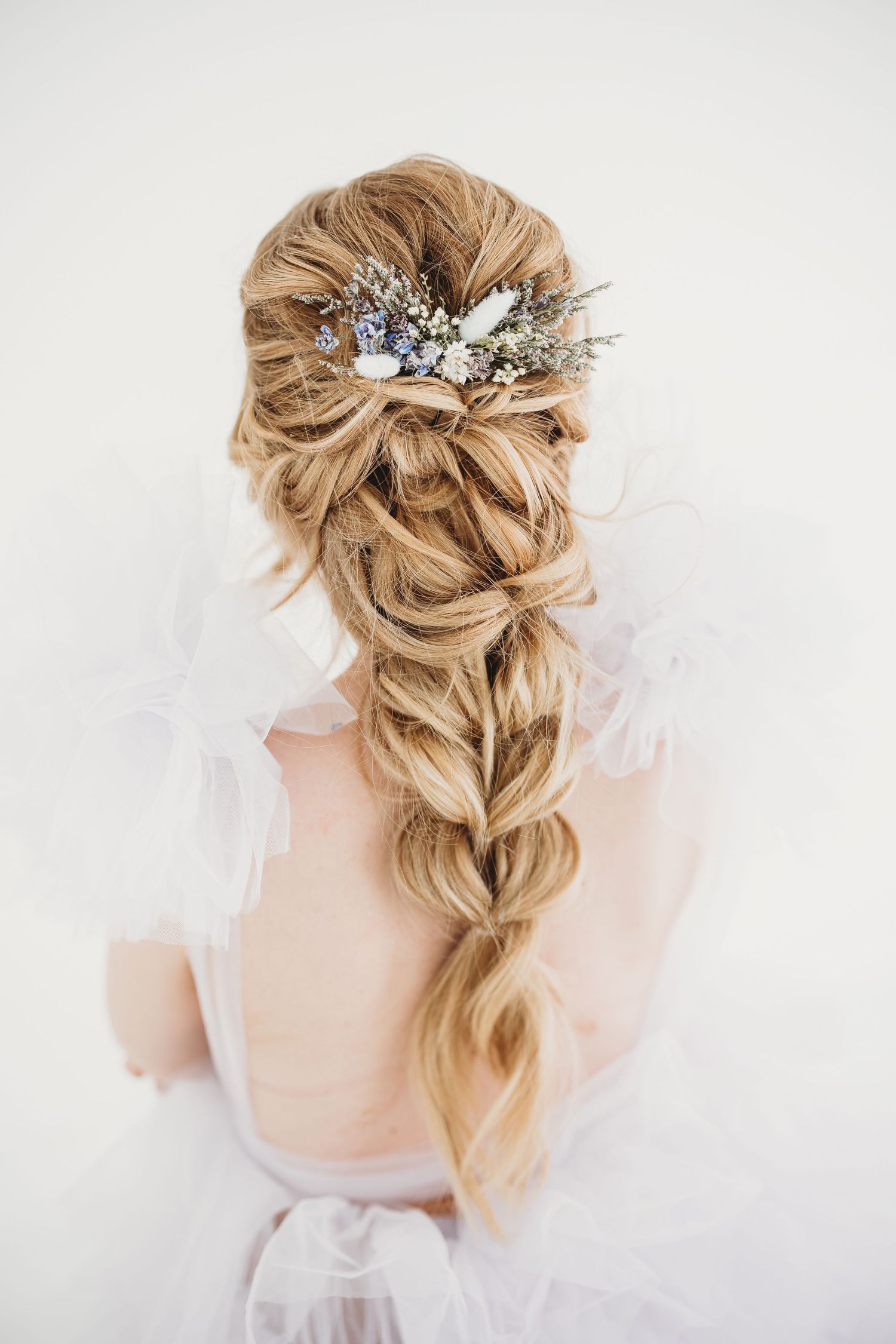 Intricate bridal hairstyle with braided blonde hair adorned with crystal and floral hair accessories.