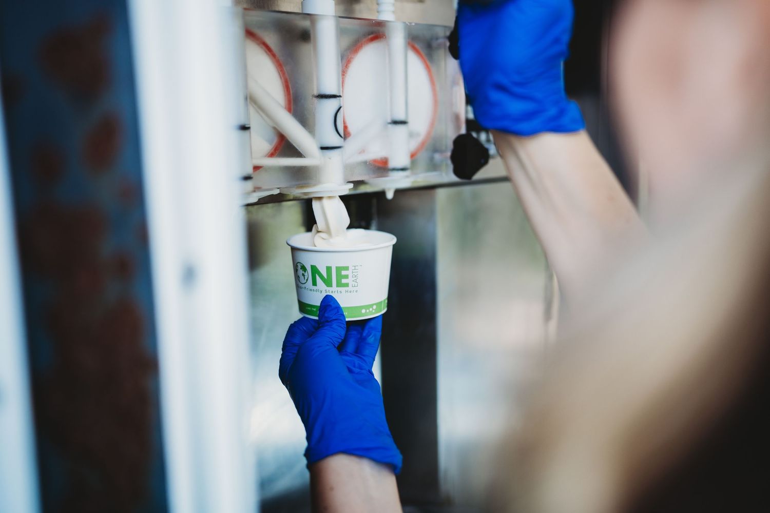 Hands in blue gloves preparing ice cream at a service station.