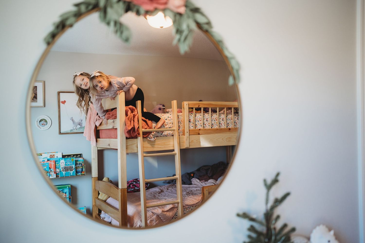 Round mirror reflection showing a cozy children's room with bunk beds and floral decorations.