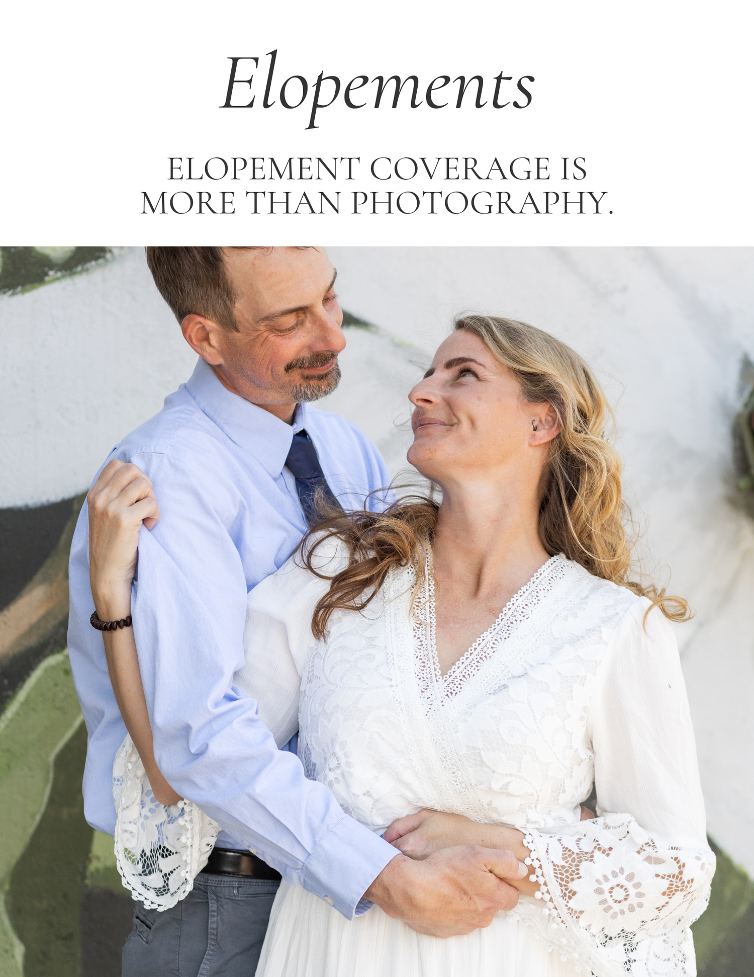 A couple shares a romantic moment during their elopement, the bride in white lace and groom in a blue shirt embracing outdoors.