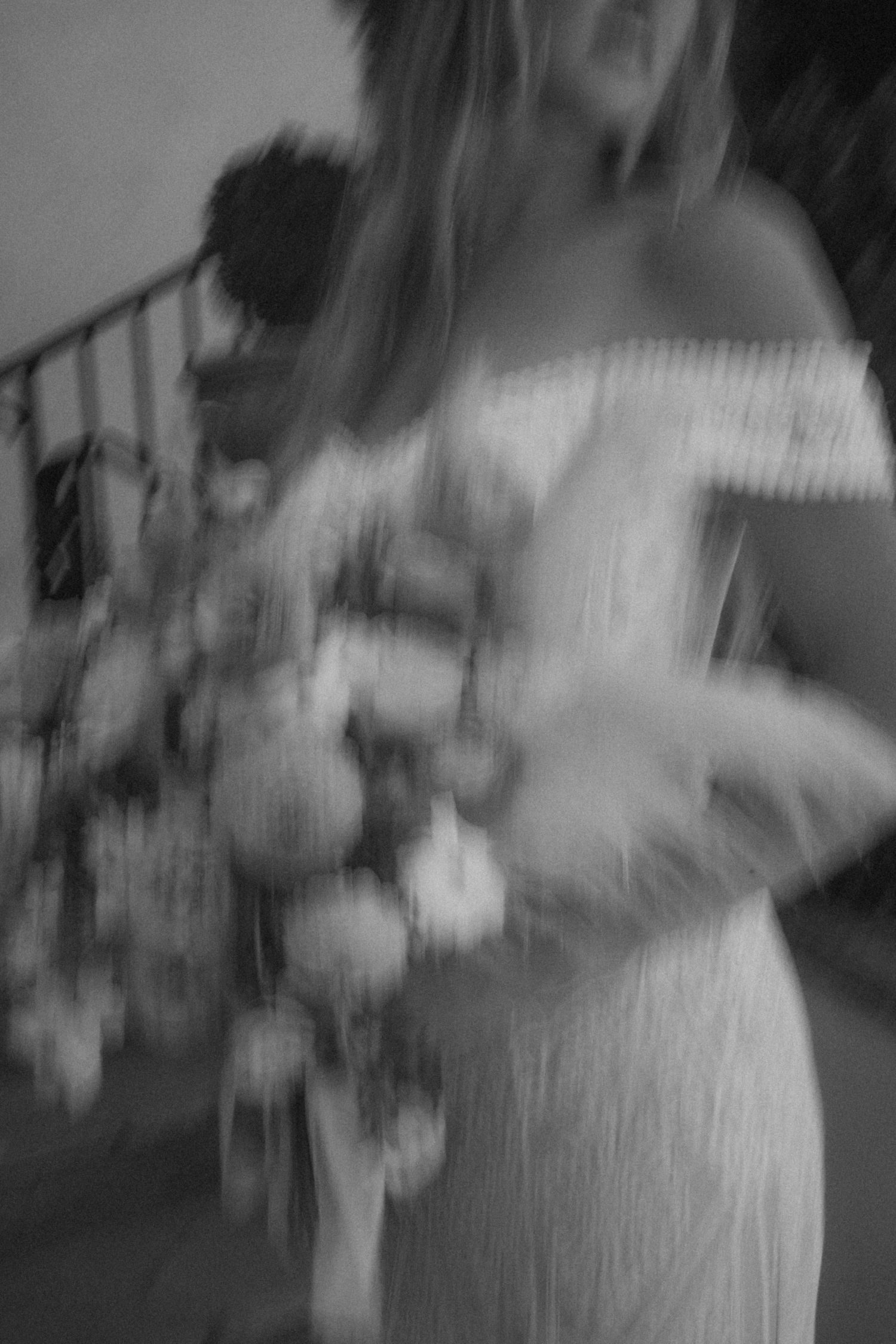 A dreamy black and white photo of a bride holding a lush floral bouquet.