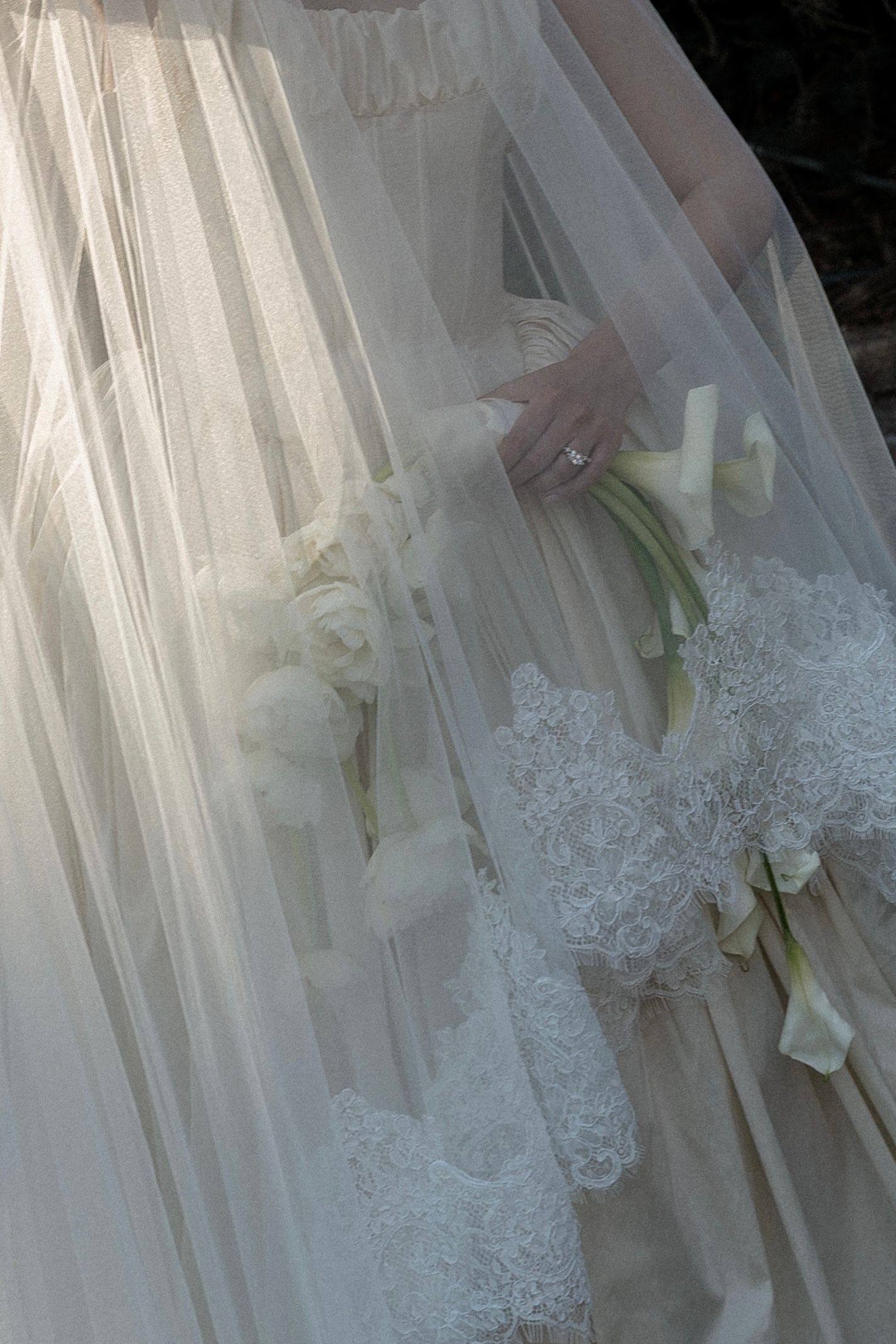 Close-up view of delicate white lace and fabric details on a wedding dress with soft natural lighting.