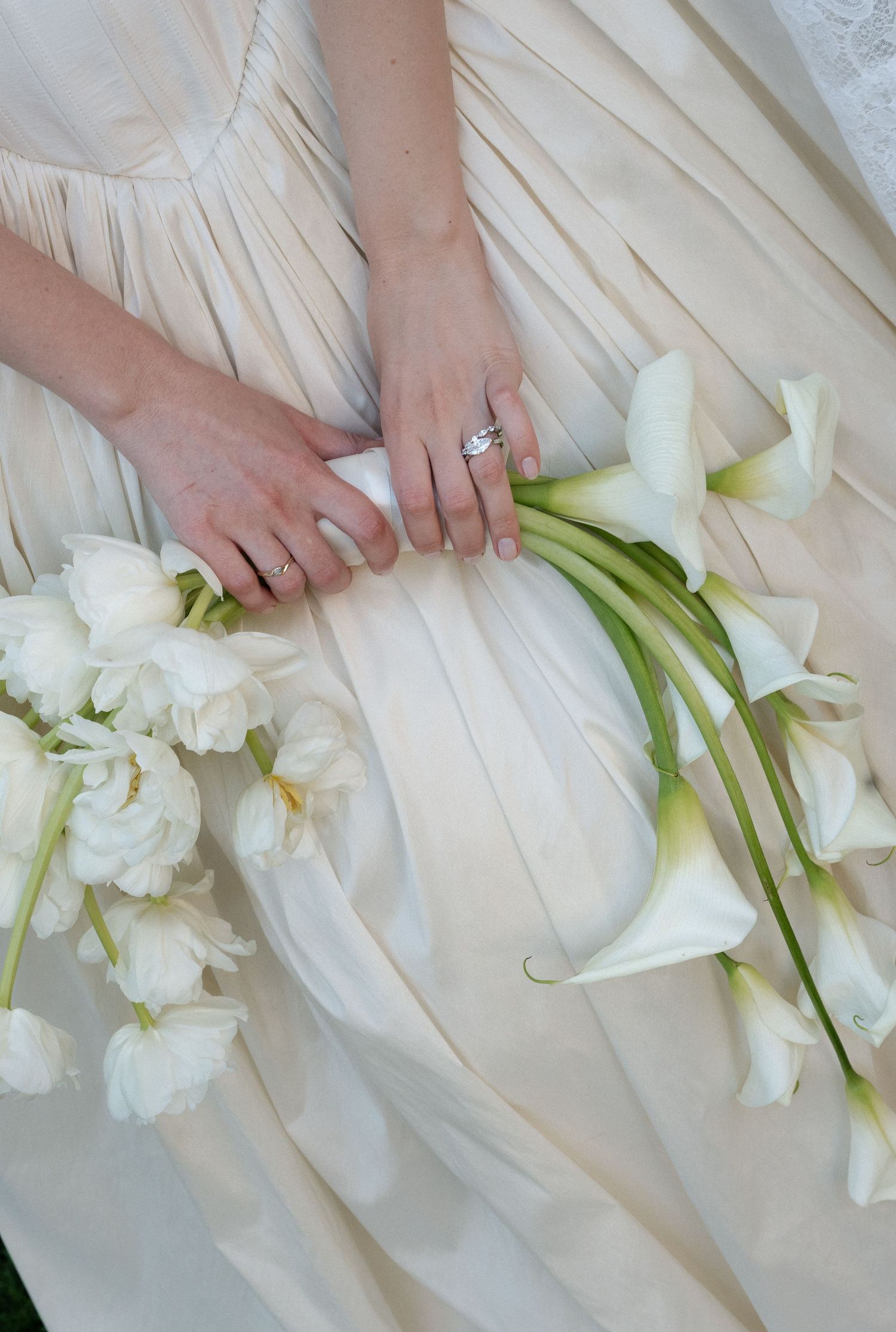 Hands arranging elegant white calla lilies and flowers on a light fabric surface in a step-by-step sequence.