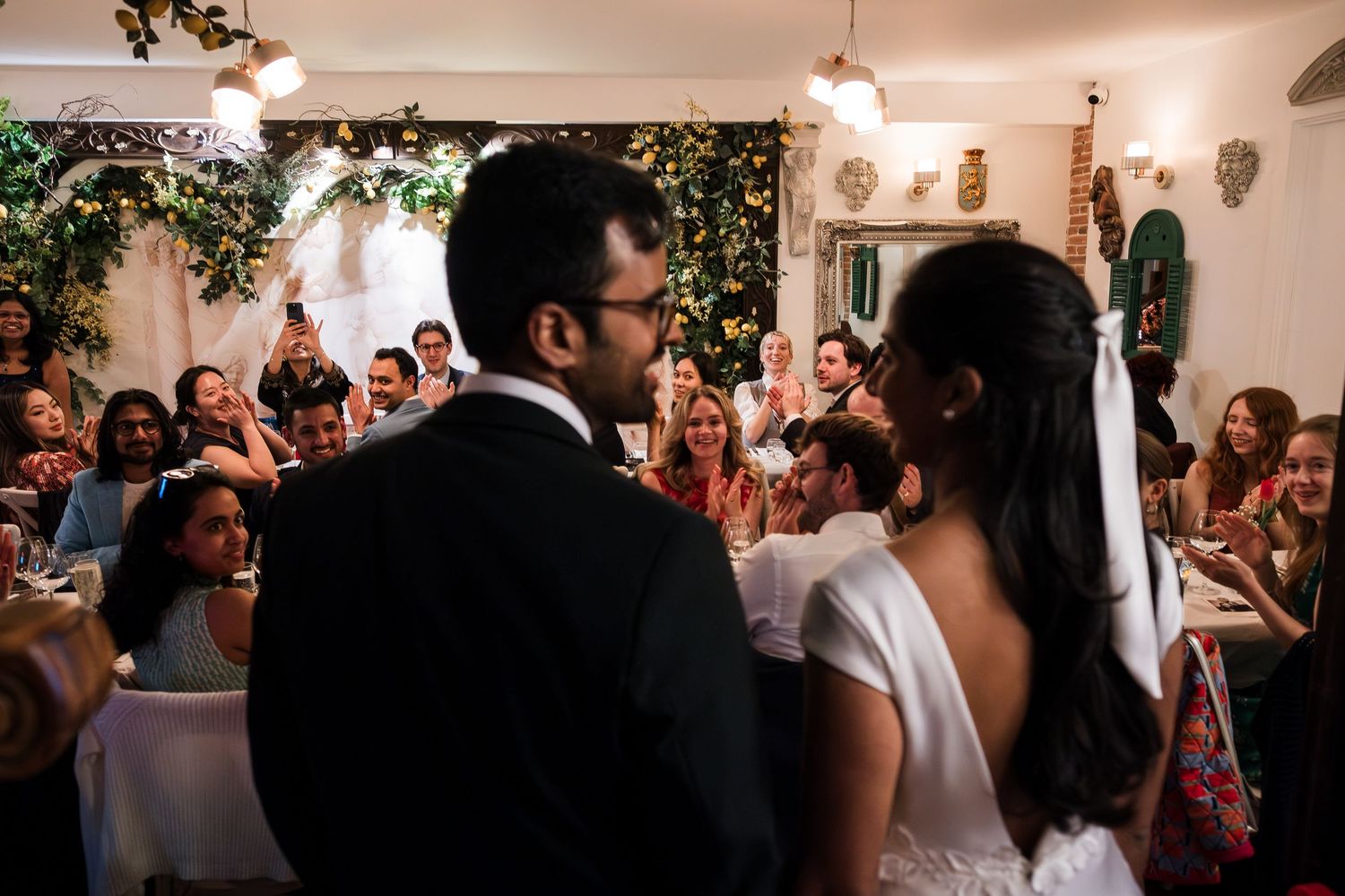 A wedding reception celebration with guests dancing and socializing in an elegant indoor venue with warm lighting.