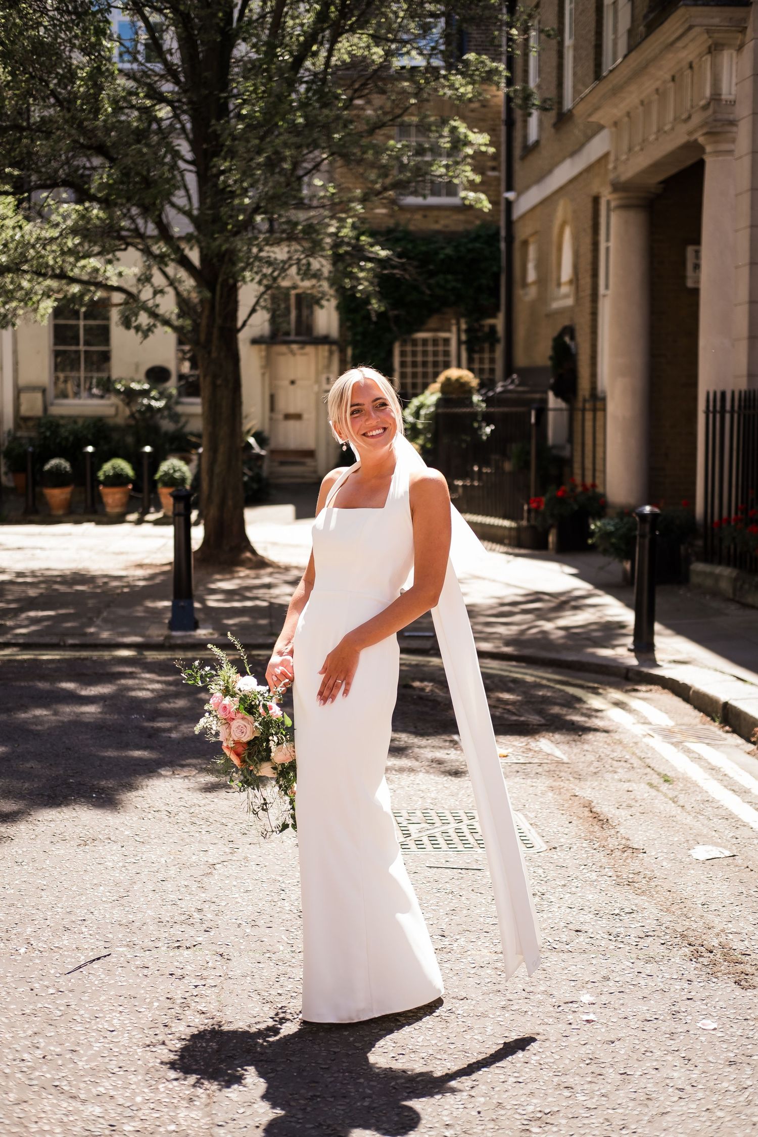 A person in an elegant white dress twirls joyfully on a sunlit cobblestone street in Paris.