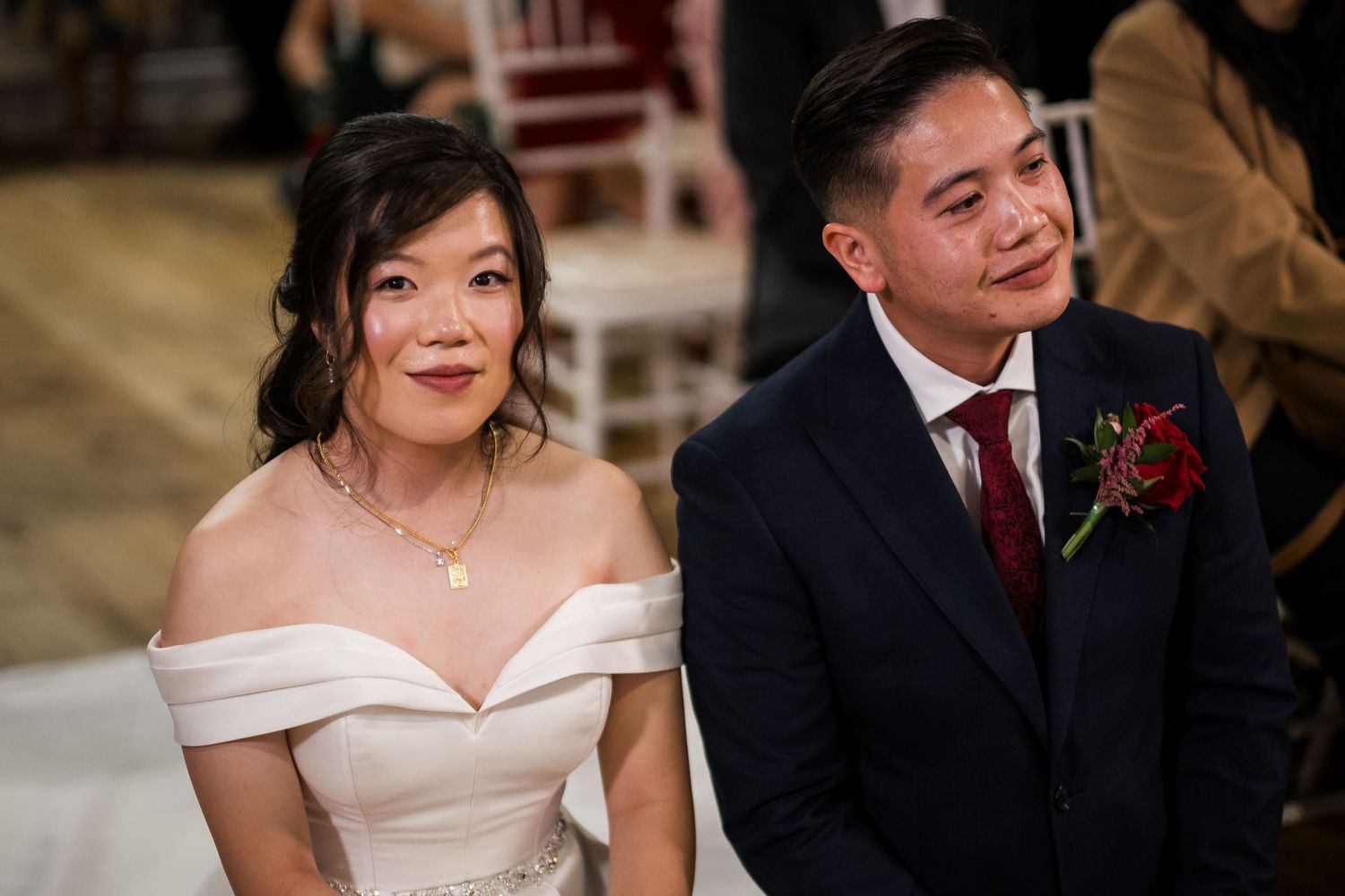 A couple shares a joyful moment during their wedding celebration, with the bride wearing an elegant off-shoulder dress.