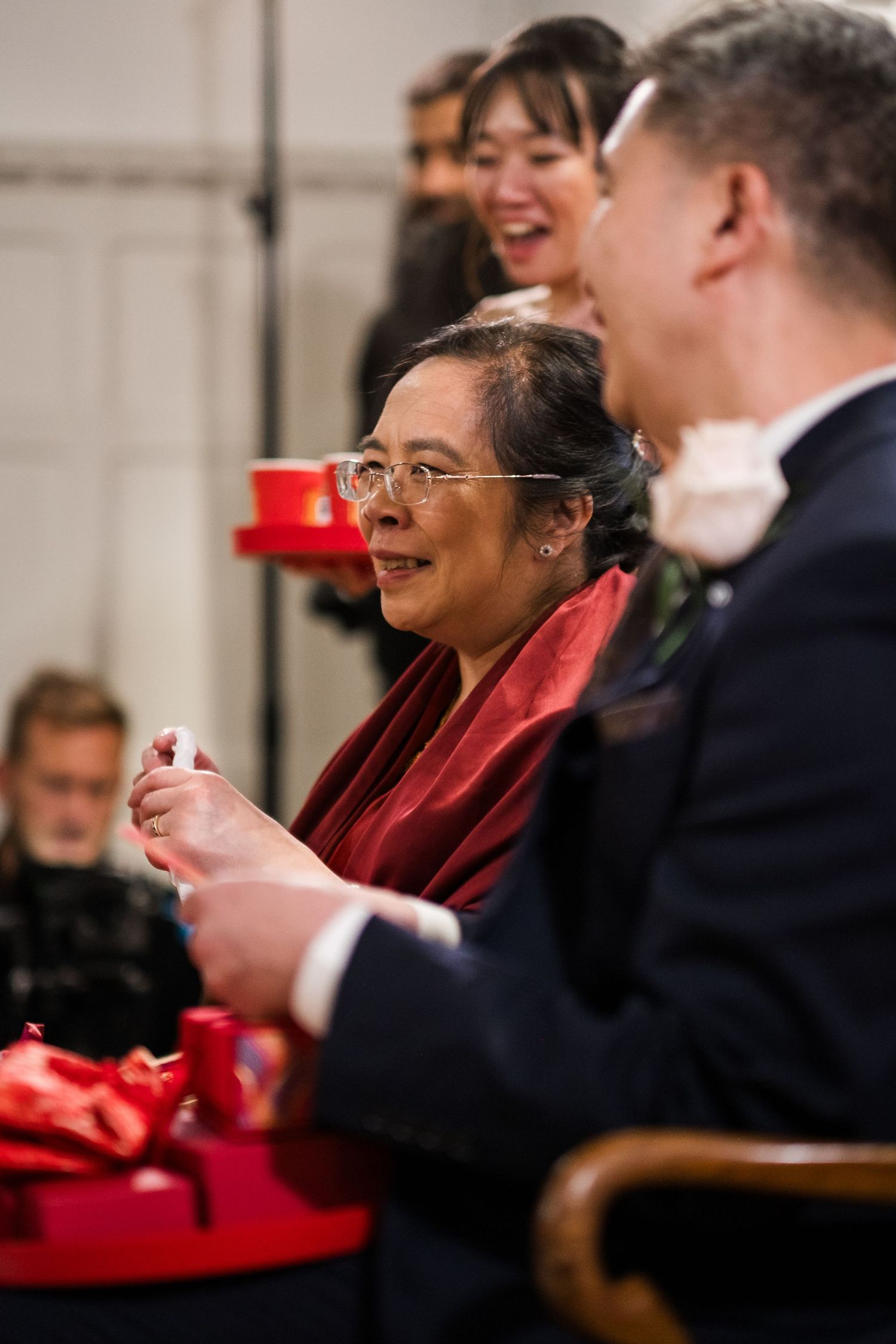 People laugh and engage in animated conversation while seated at a formal event with red table decor.
