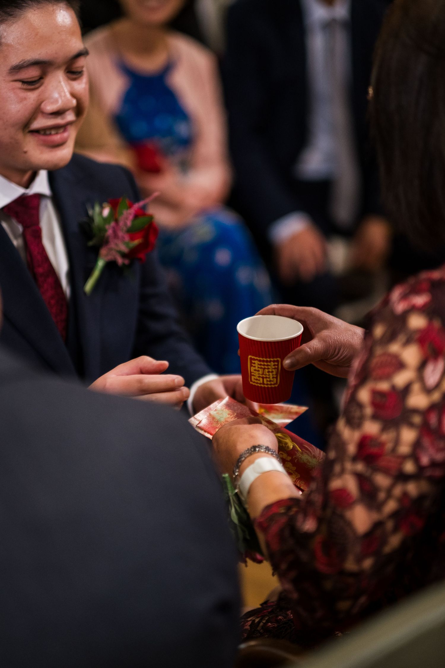 Close-up shot of hands exchanging red Chinese tea cups during traditional wedding tea ceremony.
