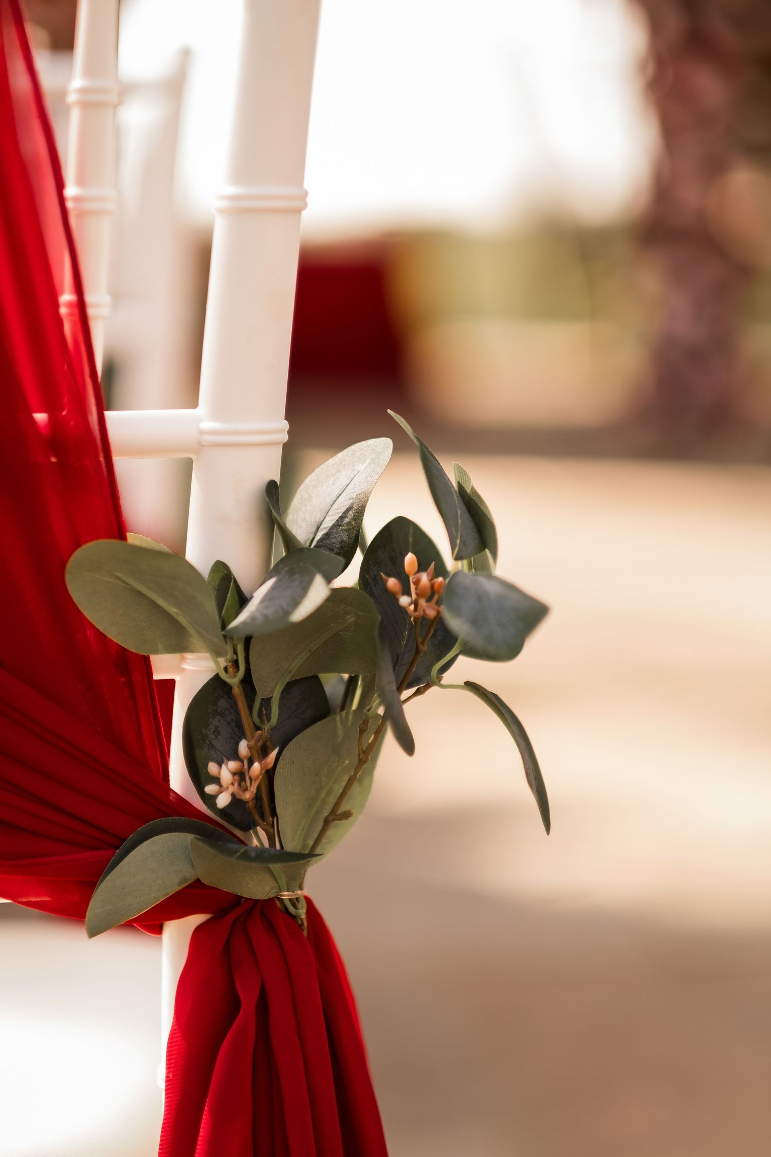 White candles with eucalyptus leaves tied with red velvet ribbon create an elegant holiday table decoration.