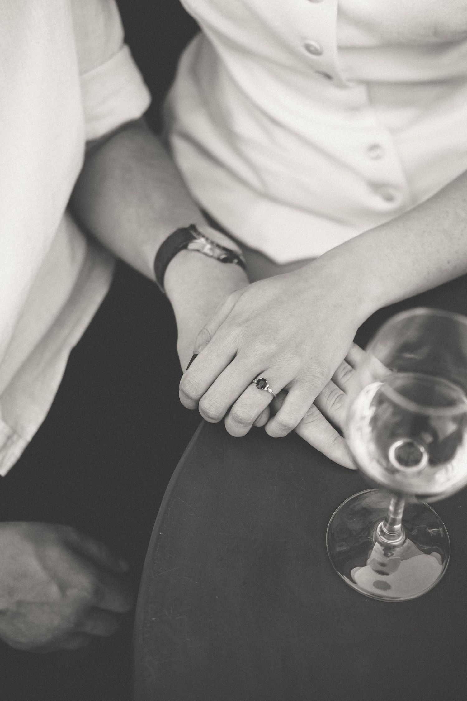 A black and white photo series showing hands holding and tilting a wine glass in different positions.