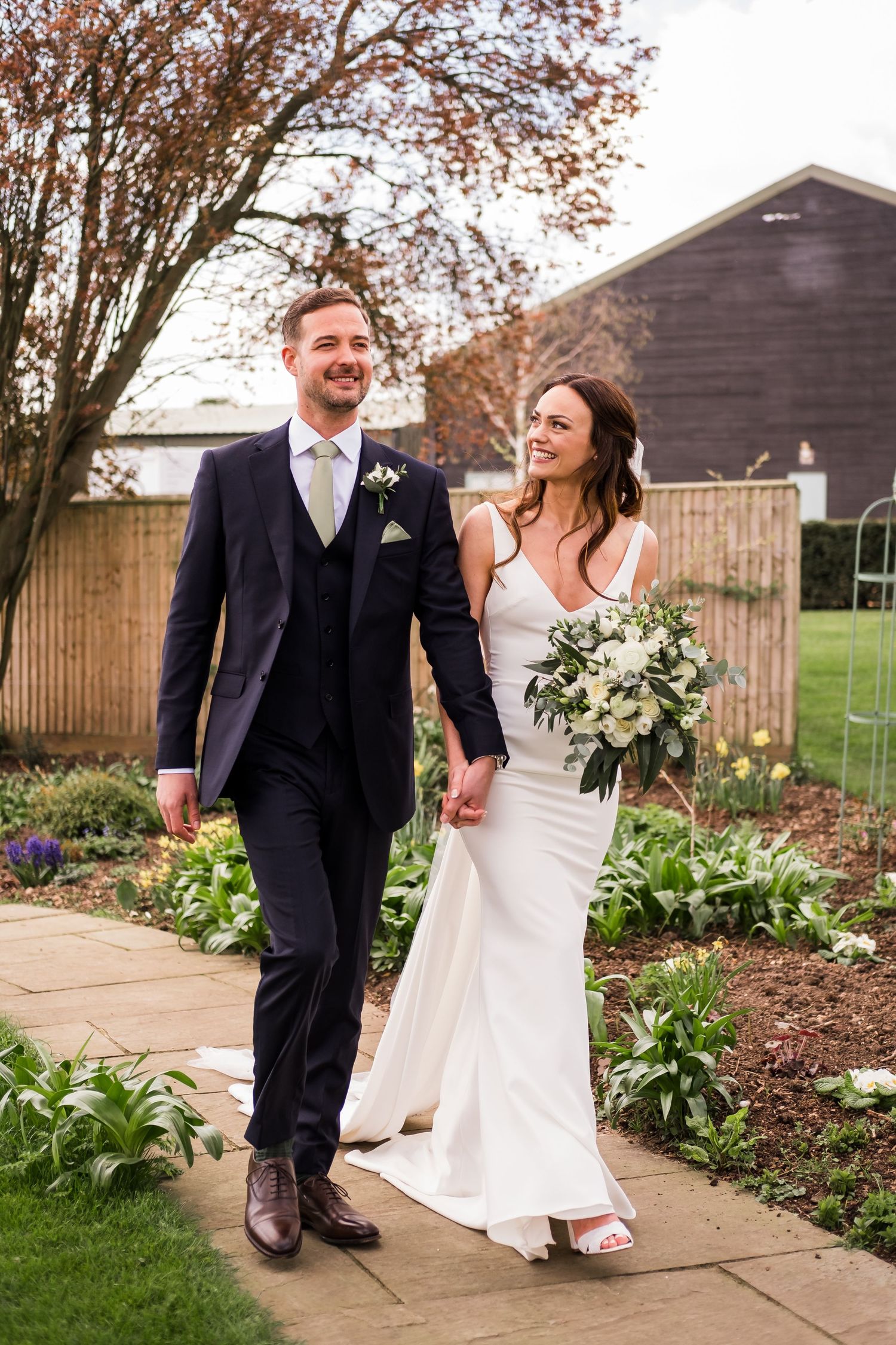 A happy couple shares joyful moments together in a garden setting during their wedding celebration.