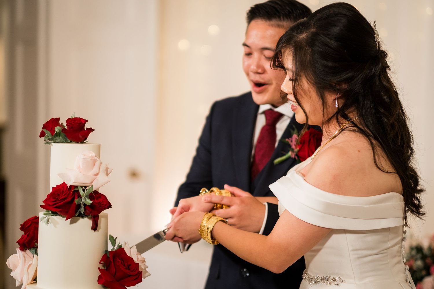 A wedding celebration moment showing a couple dancing together during their reception with red rose decor in the background.