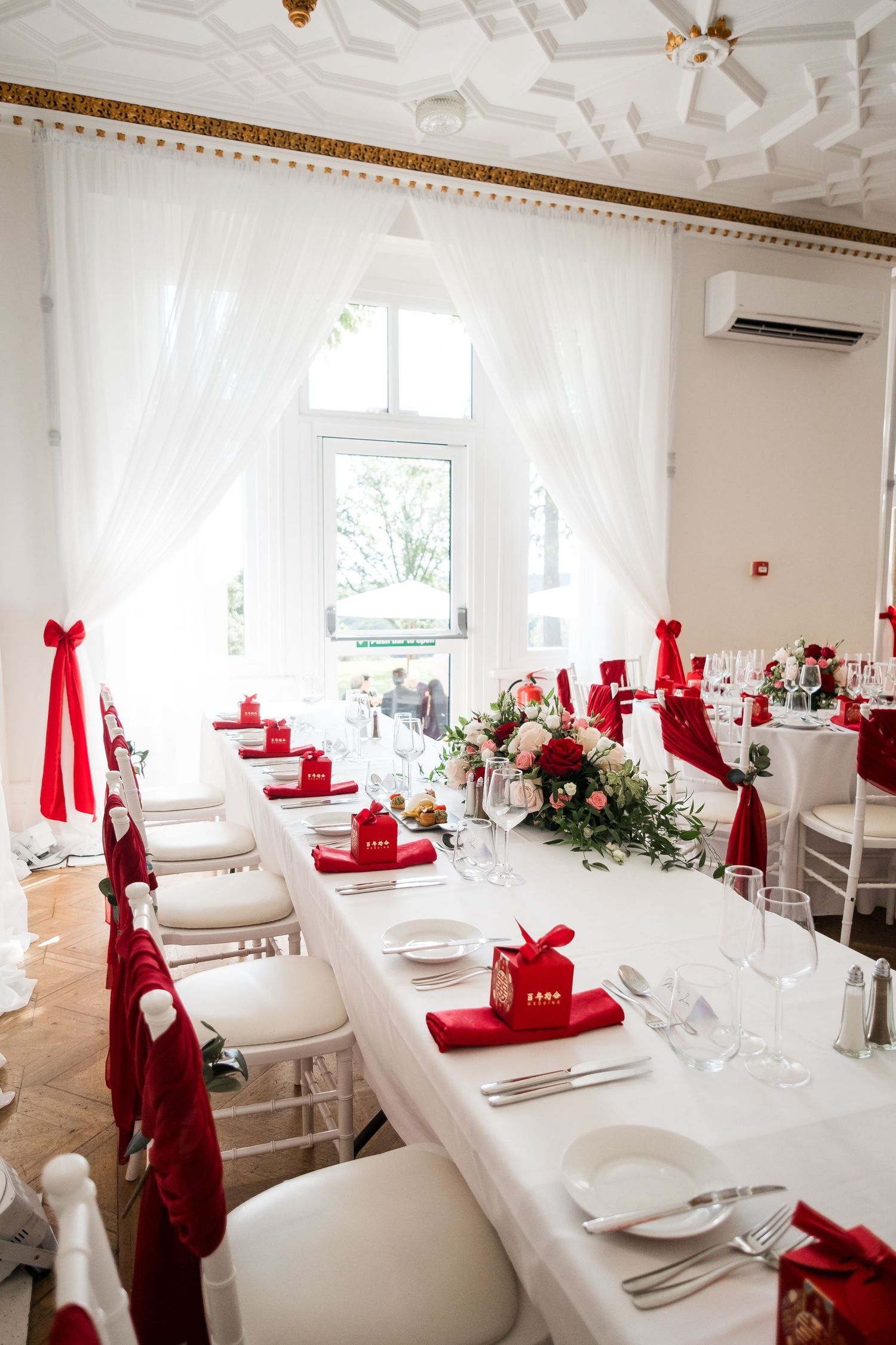Elegant white banquet hall with red napkins and table settings arranged for a formal dining event.