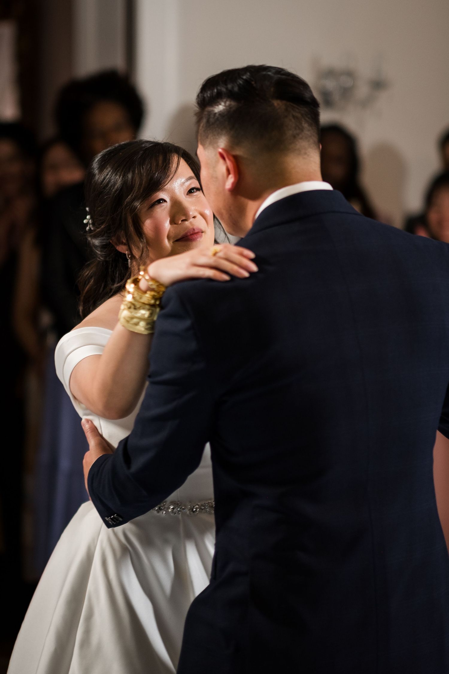 A bride and groom share an intimate embrace during their first dance at an elegant wedding reception.
