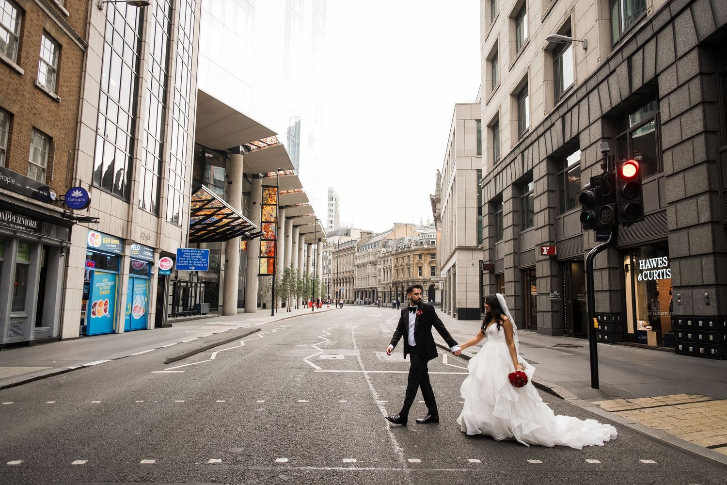 A wedding couple walks down an empty cobblestone street in Edinburgh's historic Old Town district.
