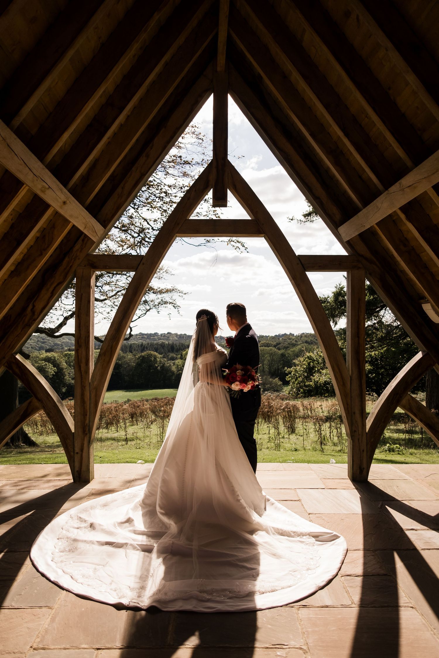 A romantic silhouette of a couple in a rustic wooden gazebo with dramatic lighting and countryside views.