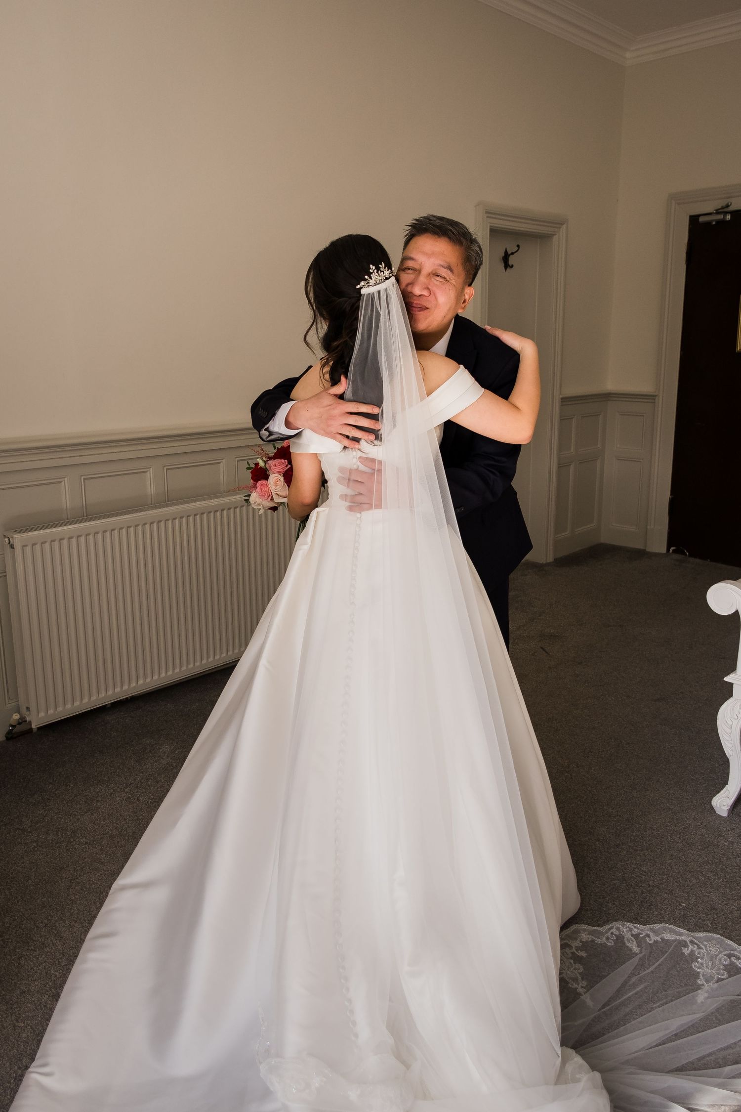 A couple shares an intimate embrace during their wedding celebration, with the bride wearing a flowing white gown and veil.