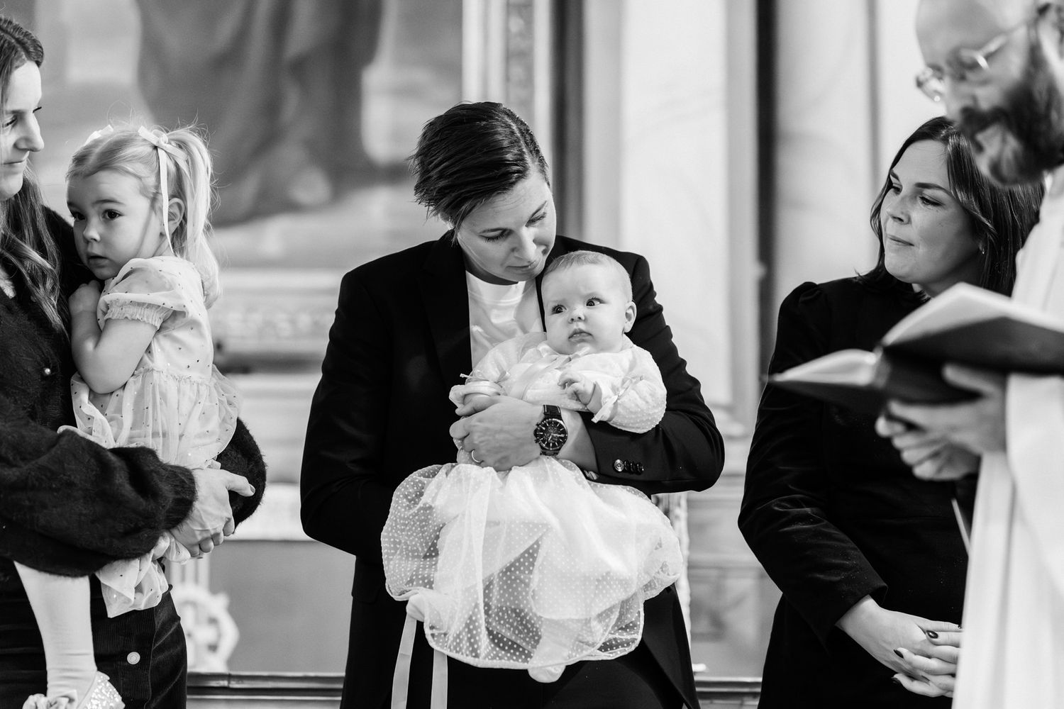 Ett dopbarn hålls av sin mamma i kyrkan under dopet.
